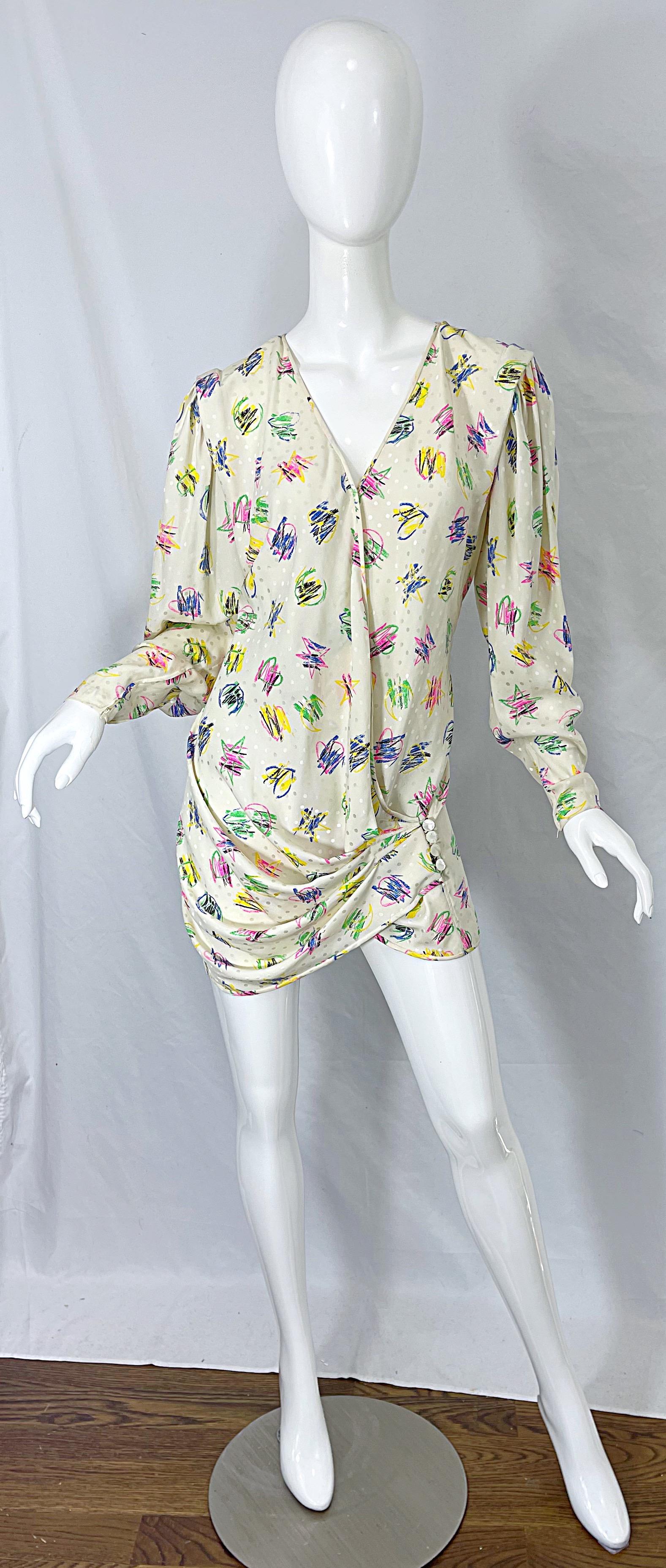 Amazing early 90s EMANUEL UNGARO novelty heart print silk wrap mini dress or blouse ! Features an ivory backdrop with vibrant colors of pink, yellow, purple, green, blue and black throughout. Inner ties with buttons at the side waist. Hidden