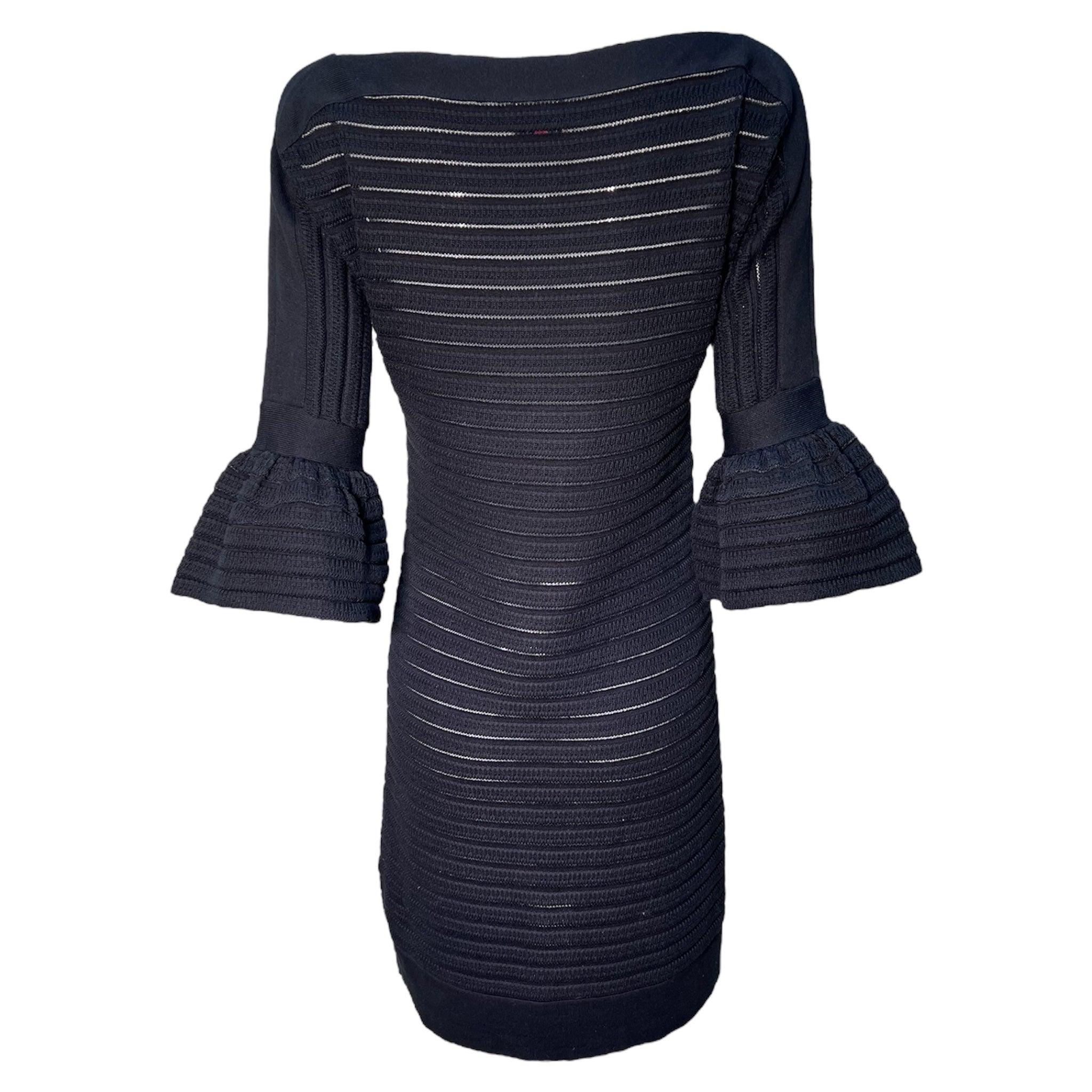 Emmanuel Ungaro - Robe à découpes en tricot noir. Vers la fin des années 1990. Des panneaux en maille avec des découpes circulaires ornent le corsage. Manches quart de longueur en péplum. Les rayures horizontales côtelées semi-transparentes créent
