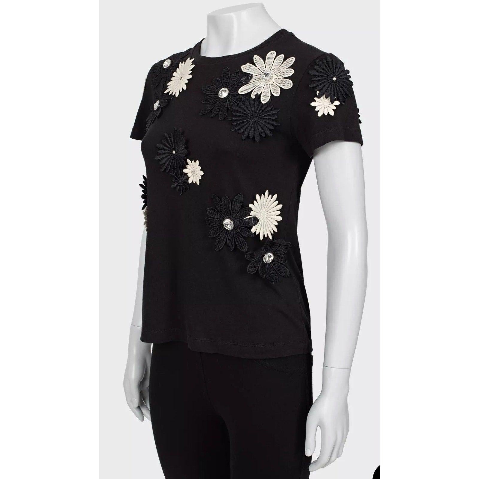 ¡Eleva tu vestuario con esta elegante camiseta de Emanuel Ungaro! 
Confeccionada en algodón 100%, esta camiseta blanca y negra presenta delicados adornos florales, una silueta recta y un clásico escote redondo.
En excelente estado, sin signos