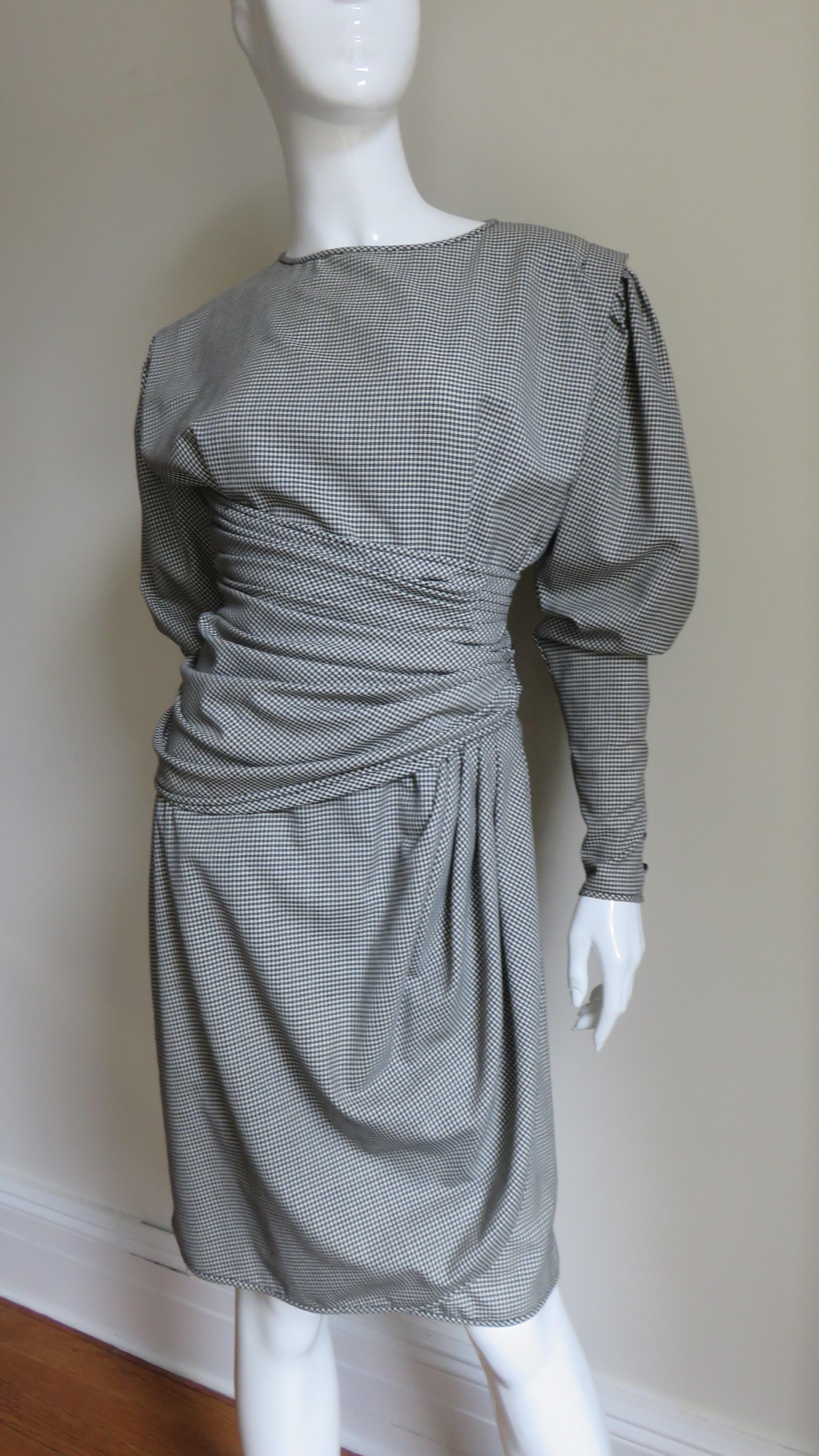 A great fine black and white small check light weight wool dress by Emanuel Ungaro. It has a crew neckline, fabulous leg o mutton sleeves with zipper and button cuffs, a wrapping draped front skirt and a horizontally ruched waist which buttons on