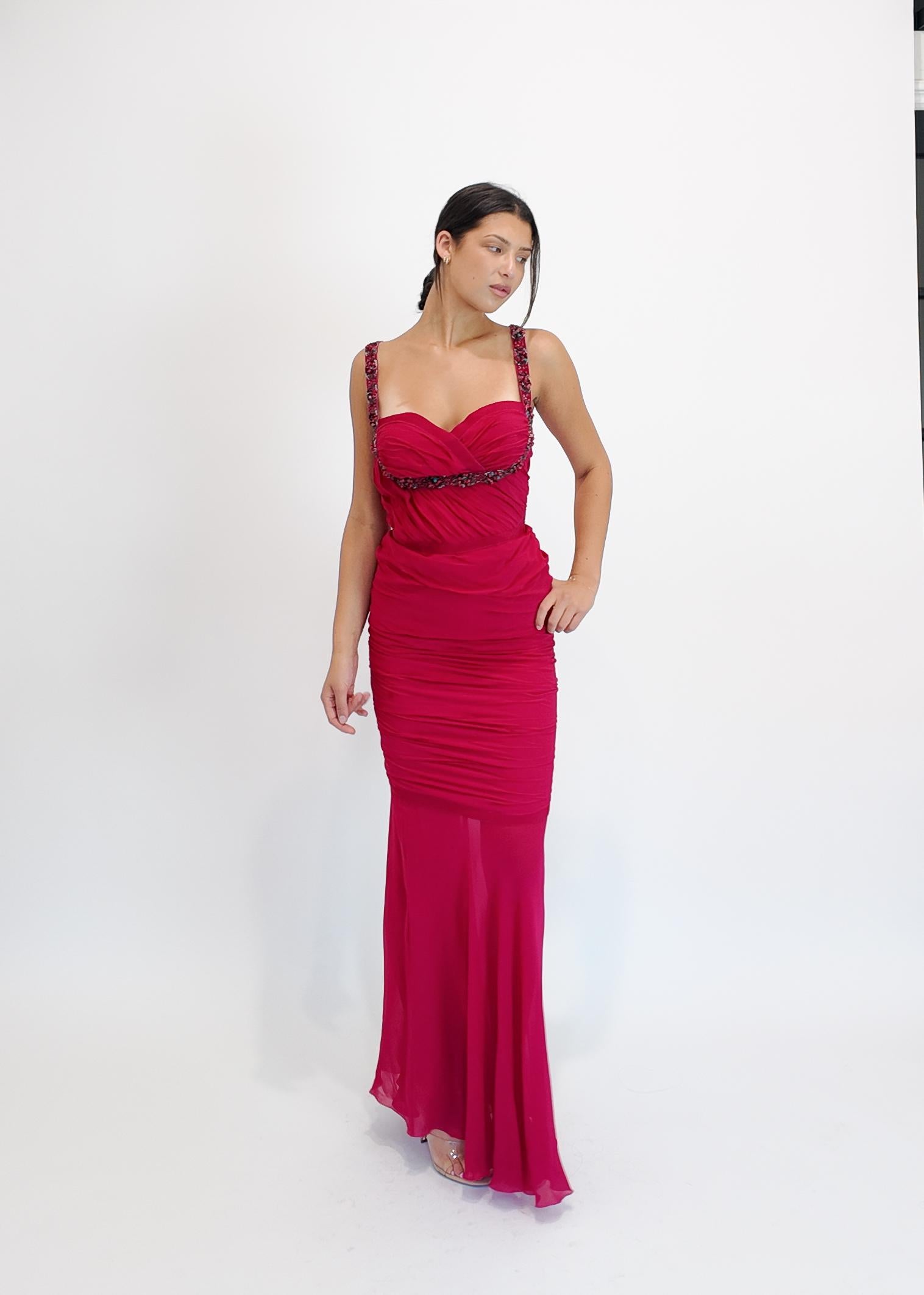 Cette robe Emanuel Ungaro d'un fuchsia éclatant présente d'élégants fronces et des perles complexes le long du buste et des bretelles, mettant en valeur sa silhouette sophistiquée. Conçue pour les bals de fin d'année ou les soirées, elle offre un