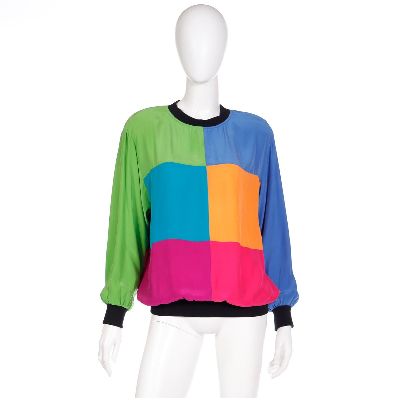 We love this easy to wear vintage Emanuel Ungaro long sleeve pullover top. The top has fun sweatshirt styling with a black ribbed knit collar, cuffs, and hemline. The blocks of colors are in pretty shades of green, blue, orange and pink and they