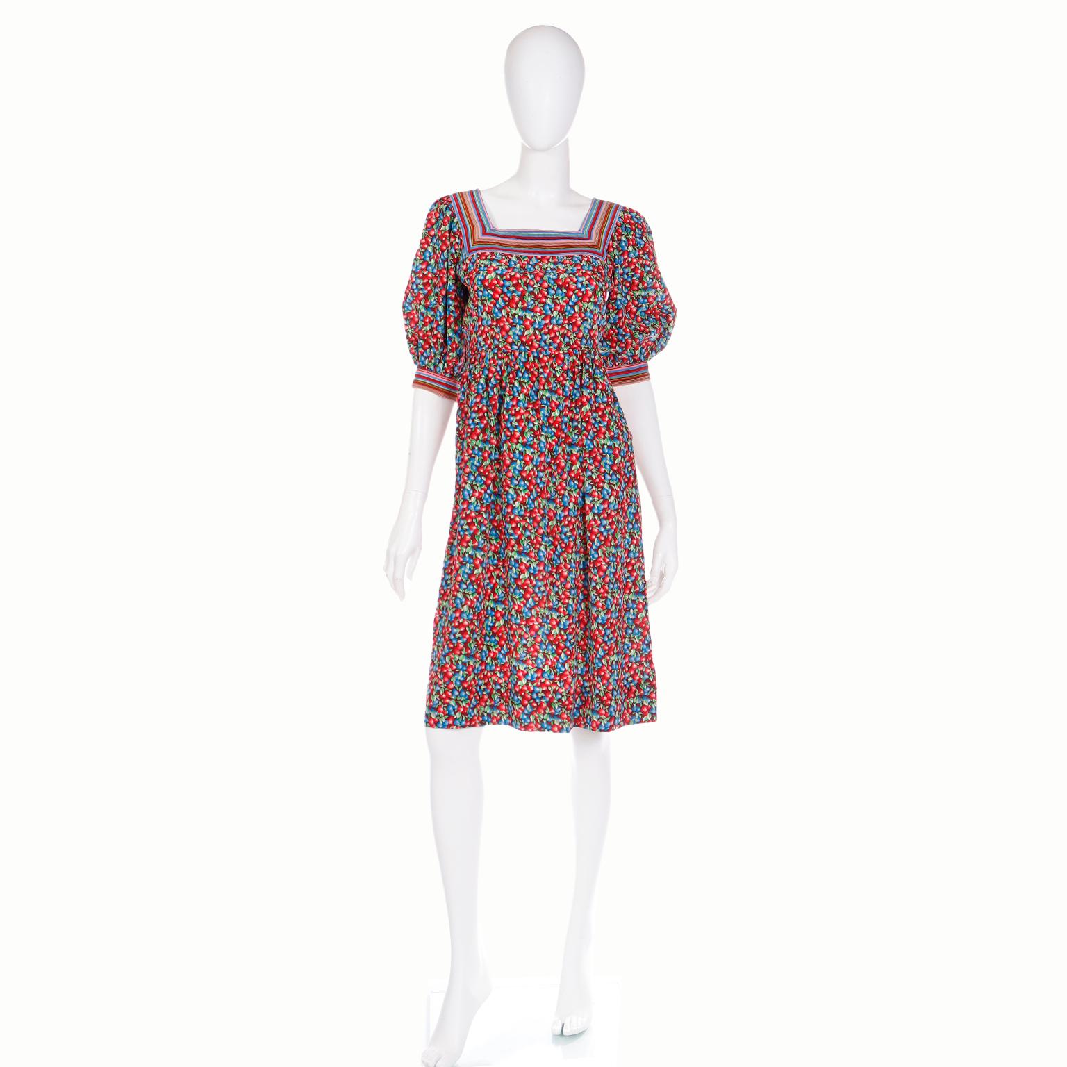 Vintage Emanuel Ungaro dresses are know for their beautiful prints and luxe fabrics. This vintage late 1970's or early 1980's silk dress is in a red and blue berry fruit print in shades of blue, red, green and pink with colorful  stripes at the
