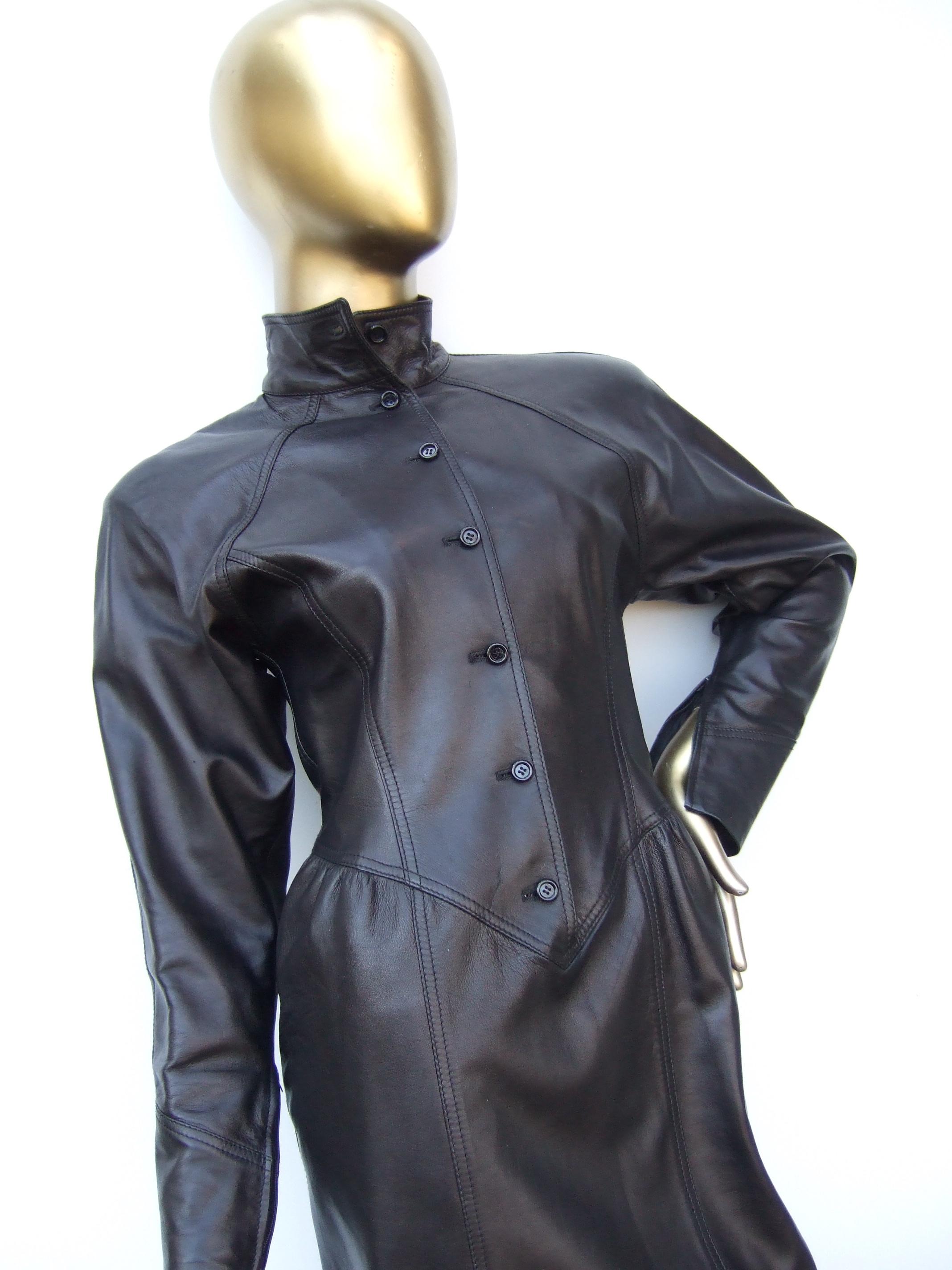Emanuel Ungaro Paris Avant-garde brown leather dress Made in Italy c 1980s
The edgy dress is constructed with supple smooth chocolate brown leather 
A series of small black resin buttons run down the front
The sleeve openings have a zippered
