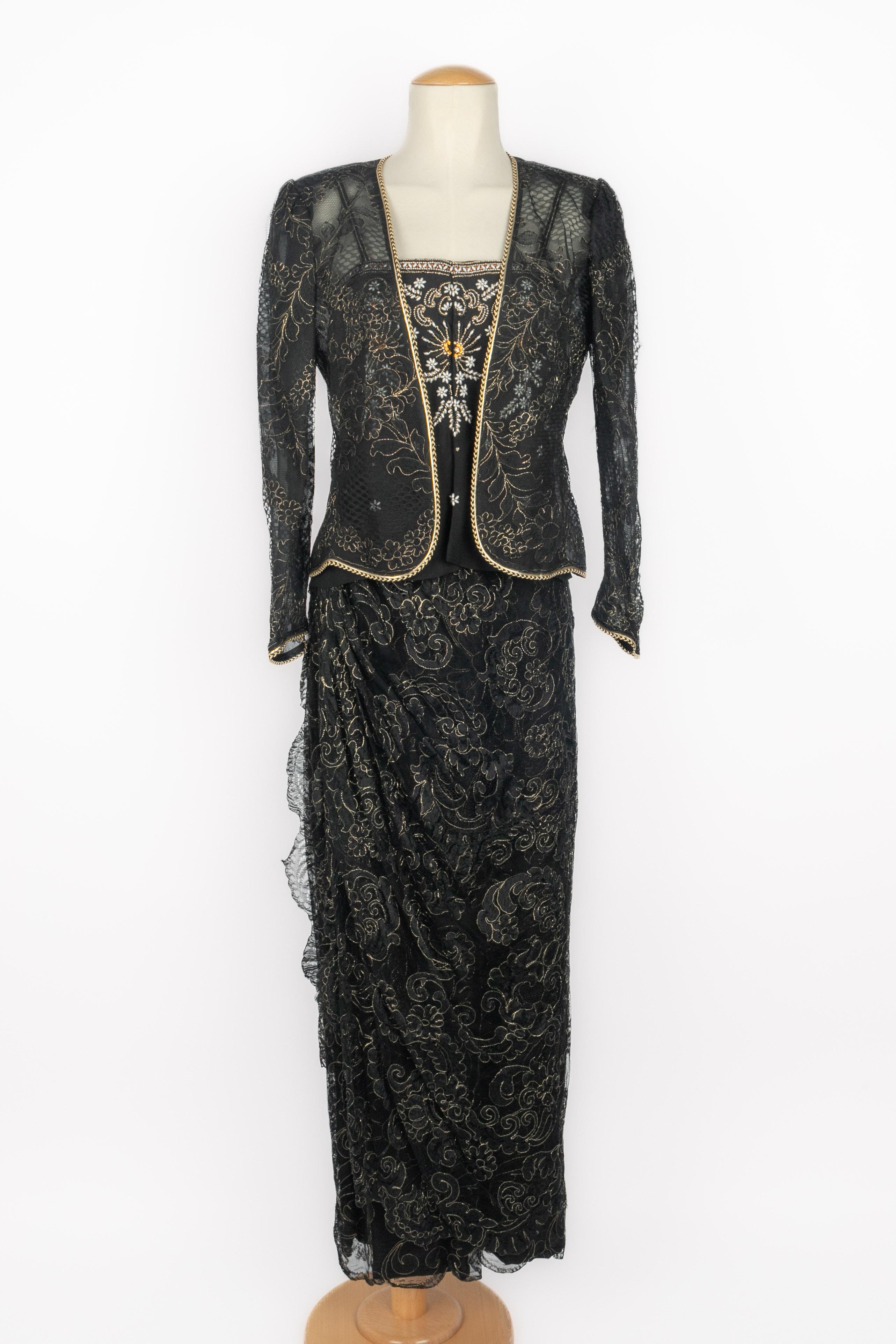 UNGARO - (Fabriqué en France) Ensemble du soir en dentelle mécanique dorée et noire composé d'une veste boléro à manches longues garnie d'un galon doré et noir sans boutons, et d'une jupe droite boutonnée. L'ensemble comprend un haut en soie noire