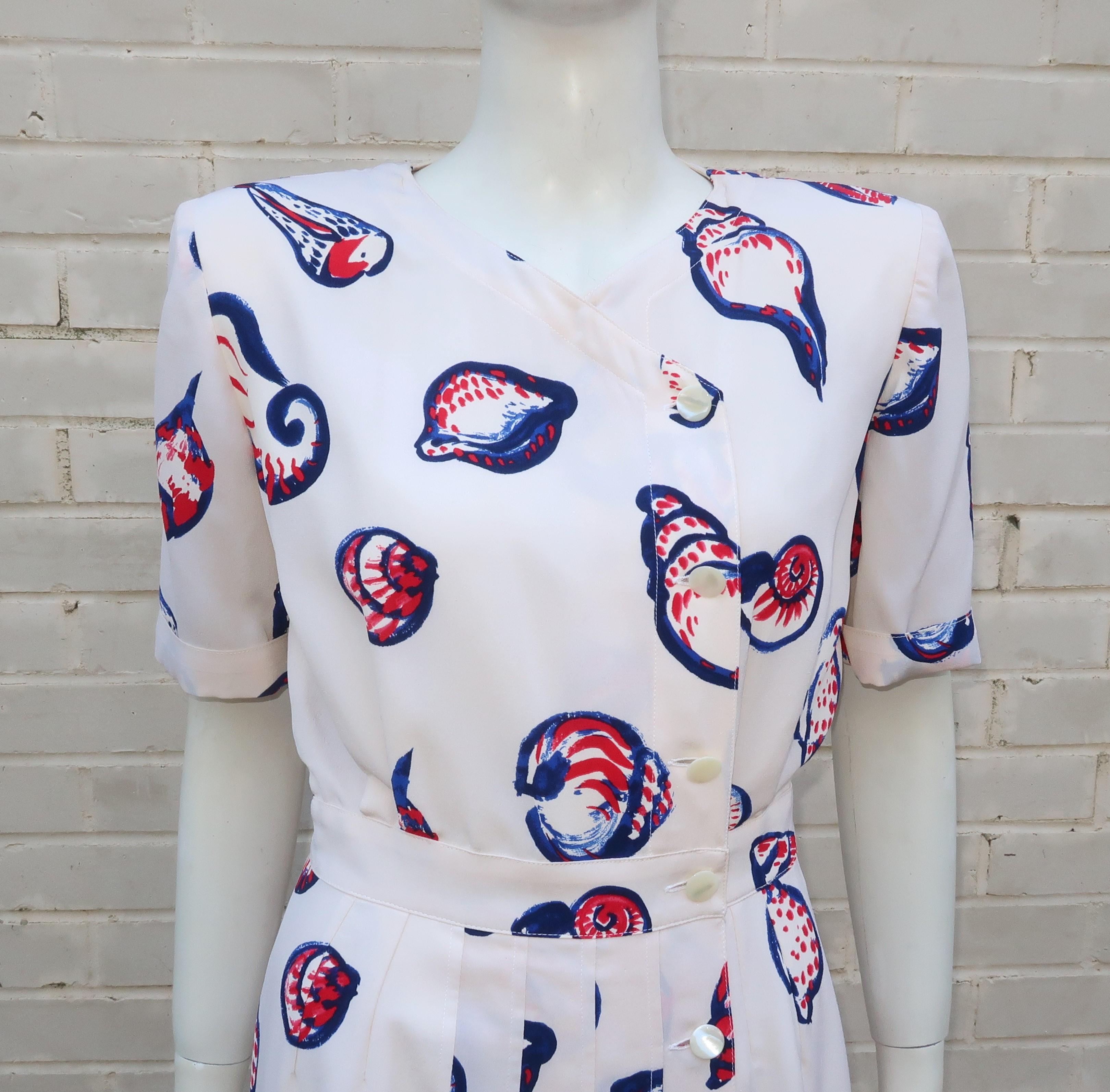 Emanuel Ungaro combines a ladylike silhouette and a nautical silk fabric printed with red, white and blue sea shells to create a 1980's design with a 1940's inspiration.  The dress asymmetrically closes down the front with mother-of-pearl buttons, a