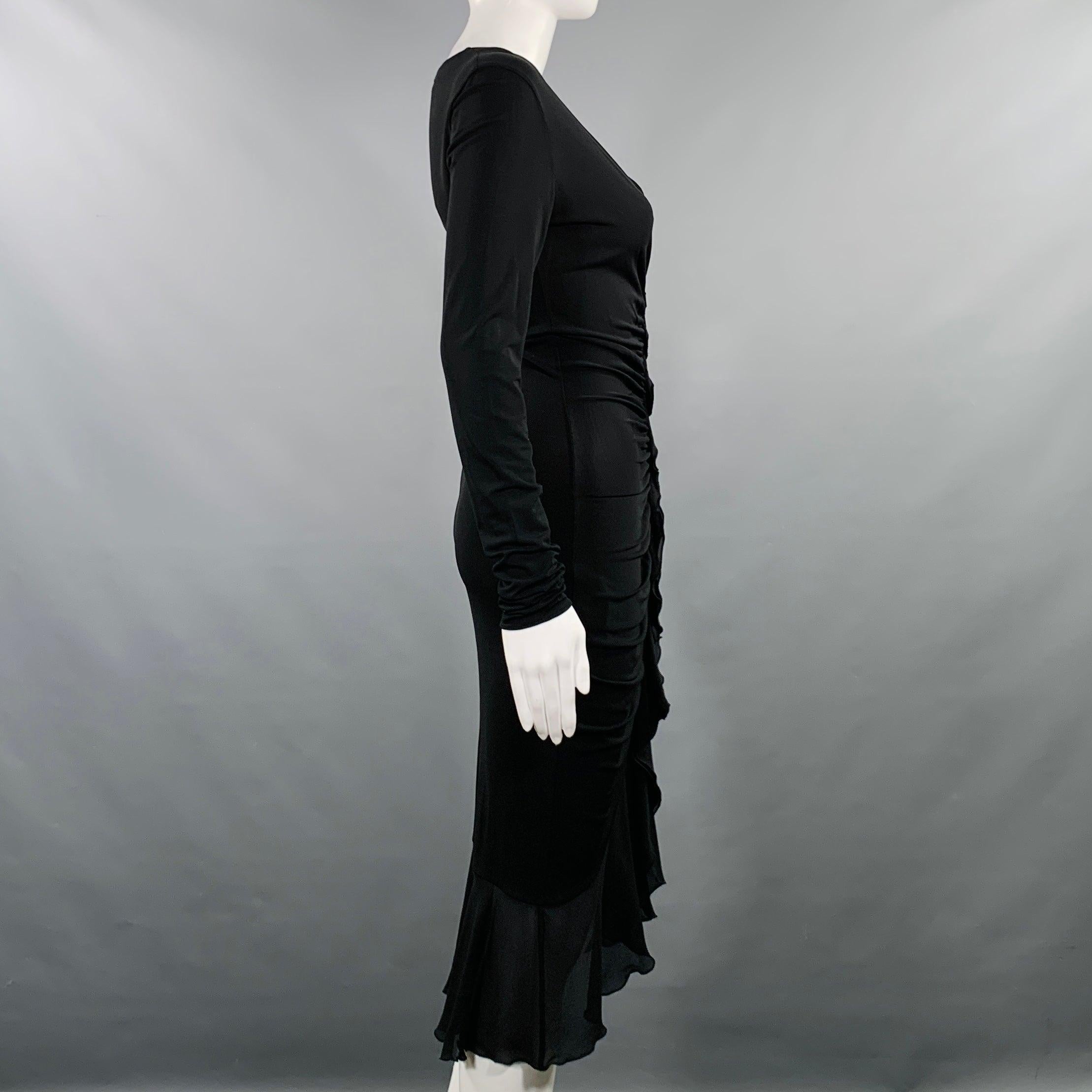 Abito da cocktail Emanuel Ungaro
in tessuto misto rayon nero, elasticizzato e aderente, con volant sul davanti e scollatura a V, maniche lunghe e gonna midi. Made in Italy. Eccellente condizione di usato. 

Contrassegnato:   IT 36 

Misure: 
