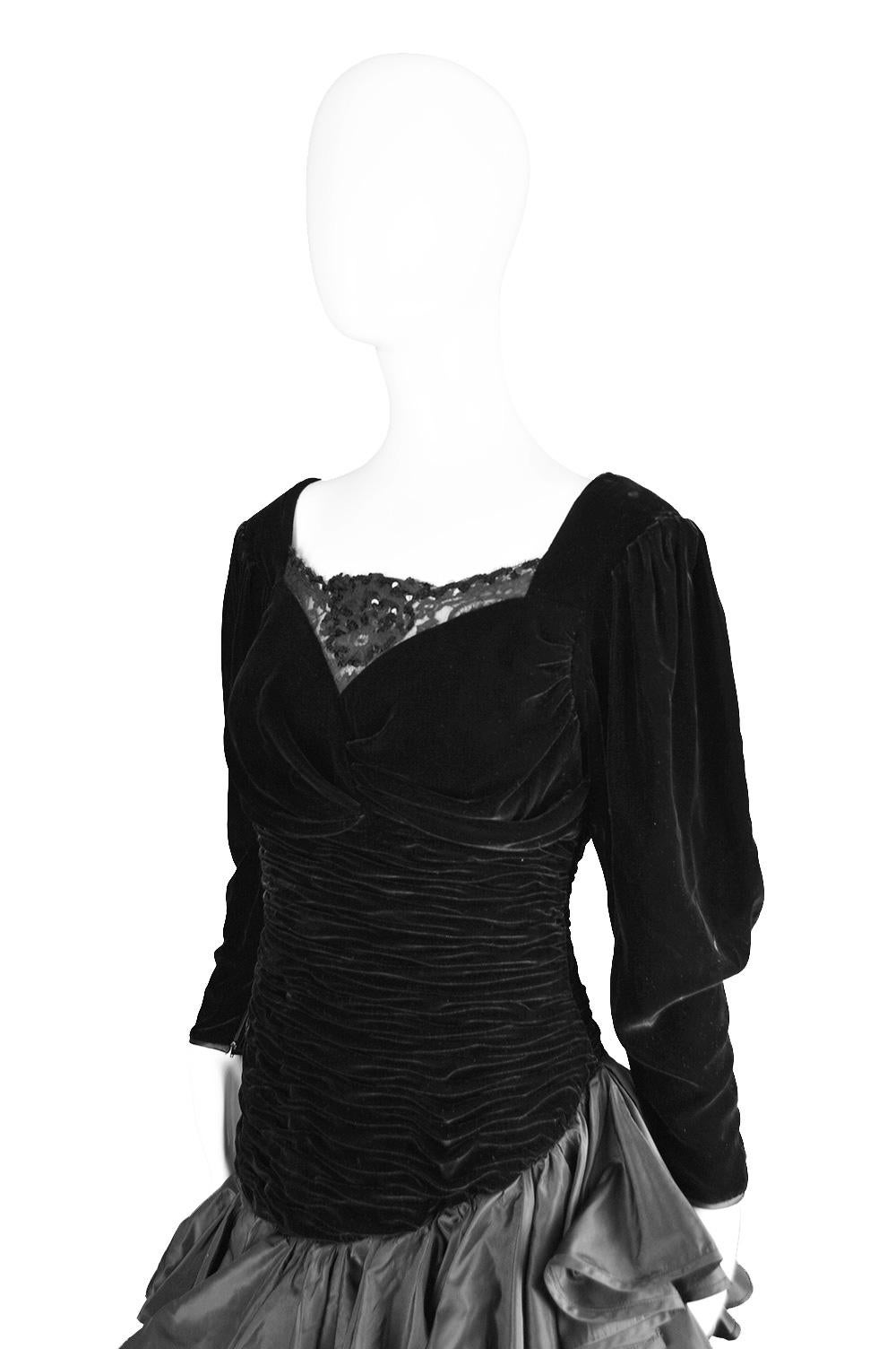 A fabulous vintage evening dress from the 80s by iconic, luxury French fashion designer, Emanuel Ungaro. In a black velvet with asymmetric black taffeta ruffles on the skirt and flattering ruching on the bodice. The neckline and the back have a