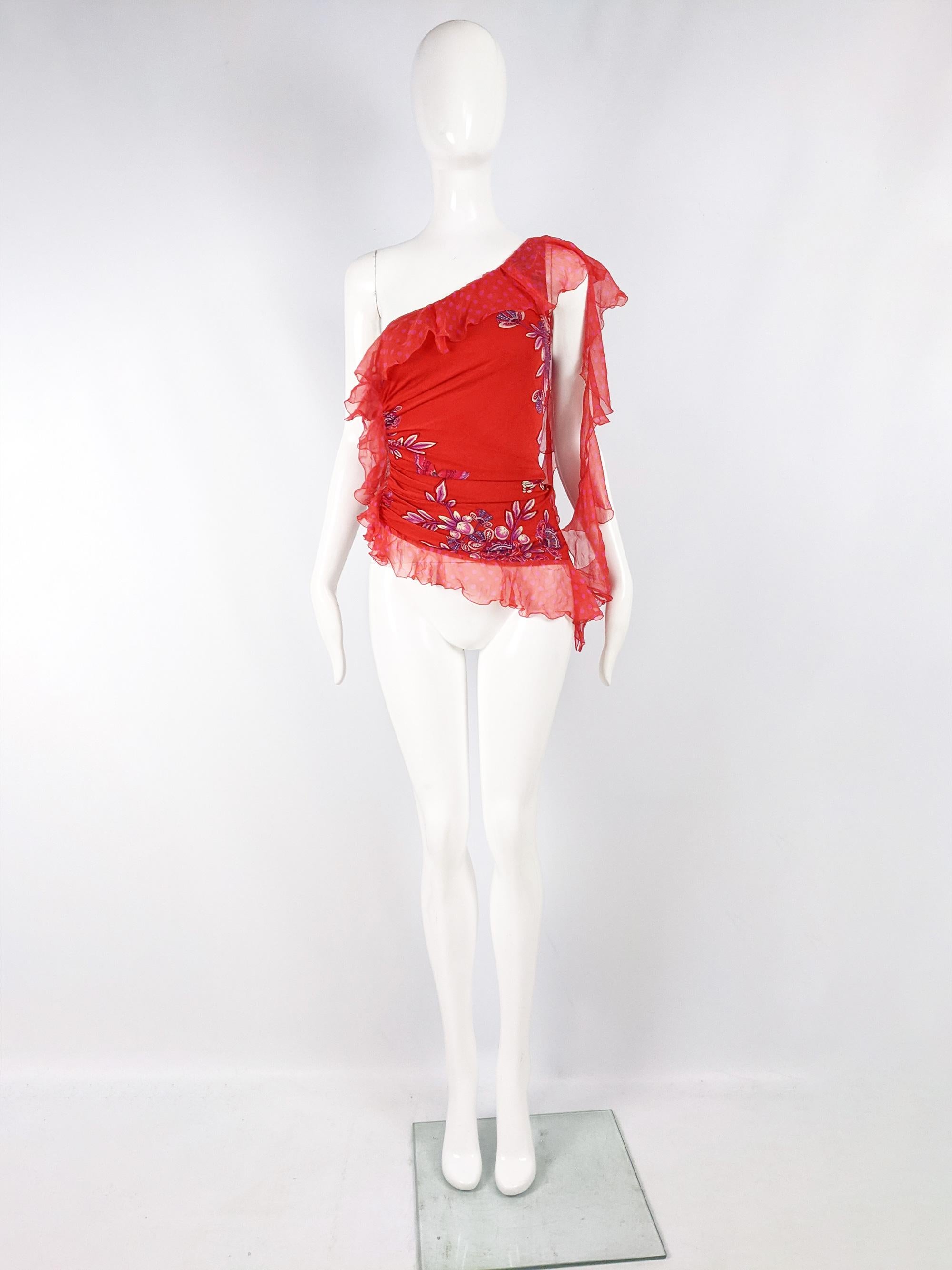 A stunning vintage womens top from the late 90s / early 00s by luxury Italian fashion designer, Emanuel Ungaro. In a red jersey with ruching at one side and an asymmetrical length. The longer side has two beautiful draped ruffles in silk chiffon for