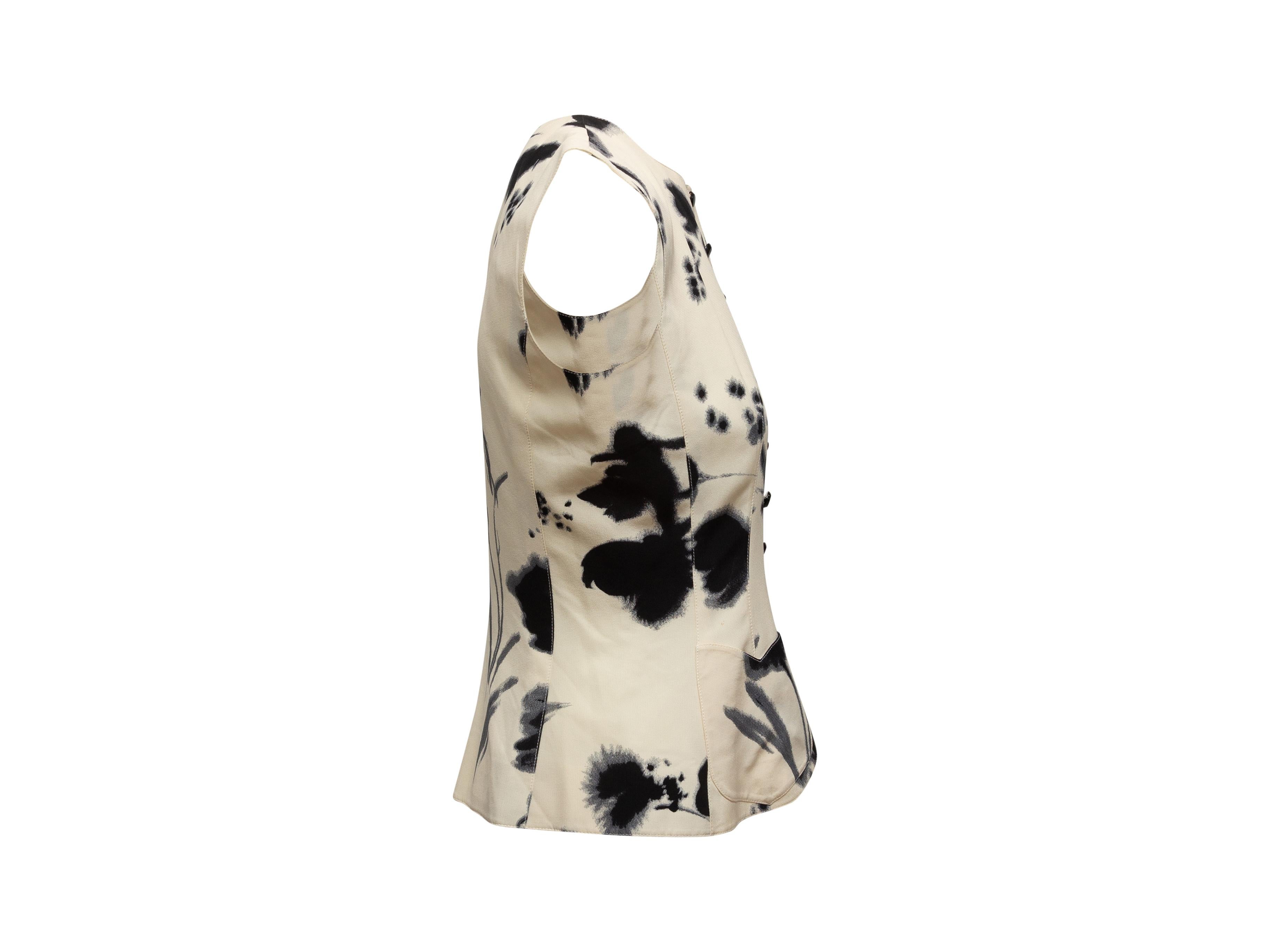 Product details: Vintage white and black silk sleeveless top by Emanuel Ungaro. Abstract floral print throughout. Crew neck. Dual patch pockets. Button closures at center front. 36