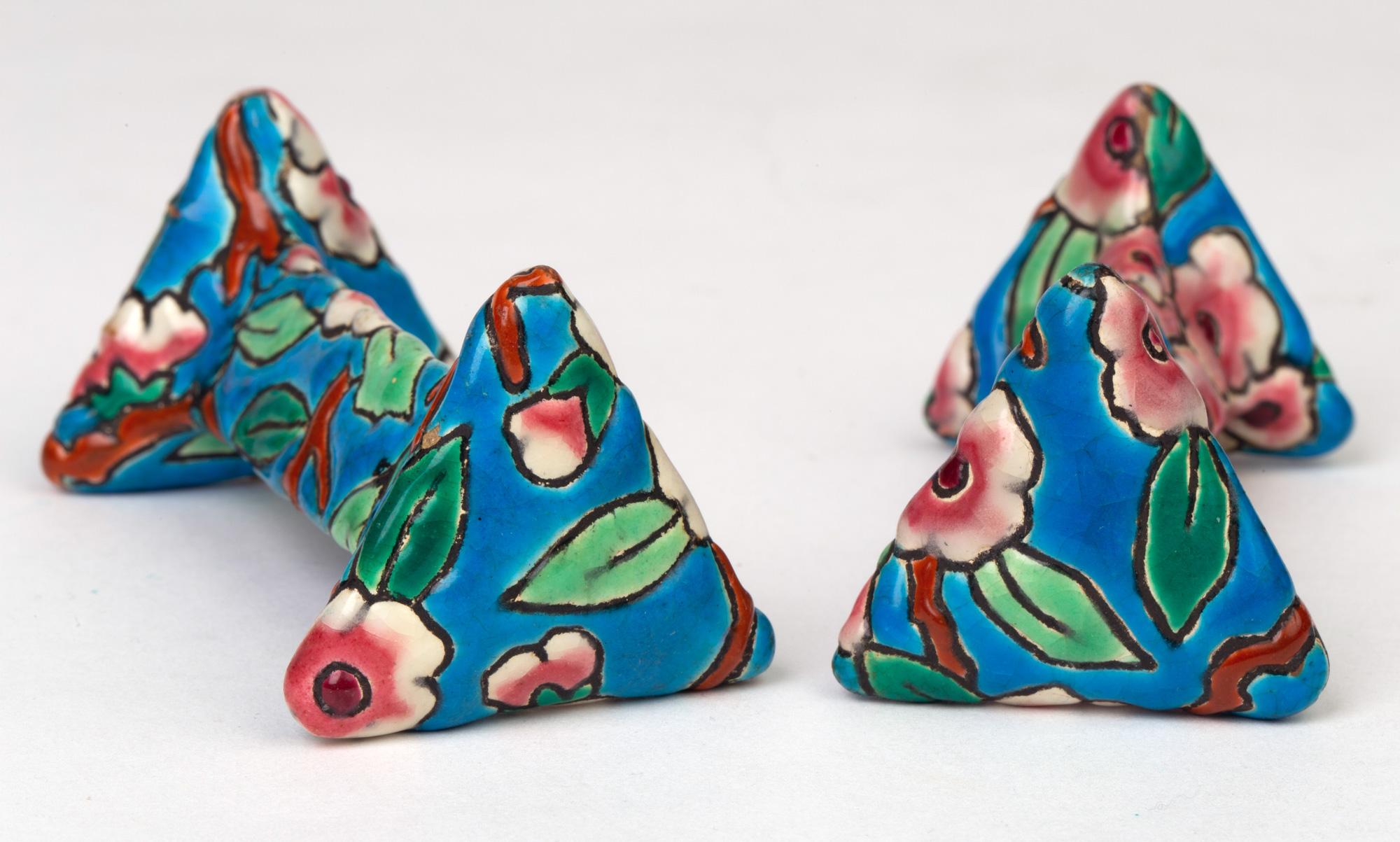A fine quality pair French Art Deco Emaux de Longwy pottery knife rests decorated in bright enamels with floral designs and dating between 1920 and 1930. The knife rests are formed in triangular shape with a triangular rest set between two larger