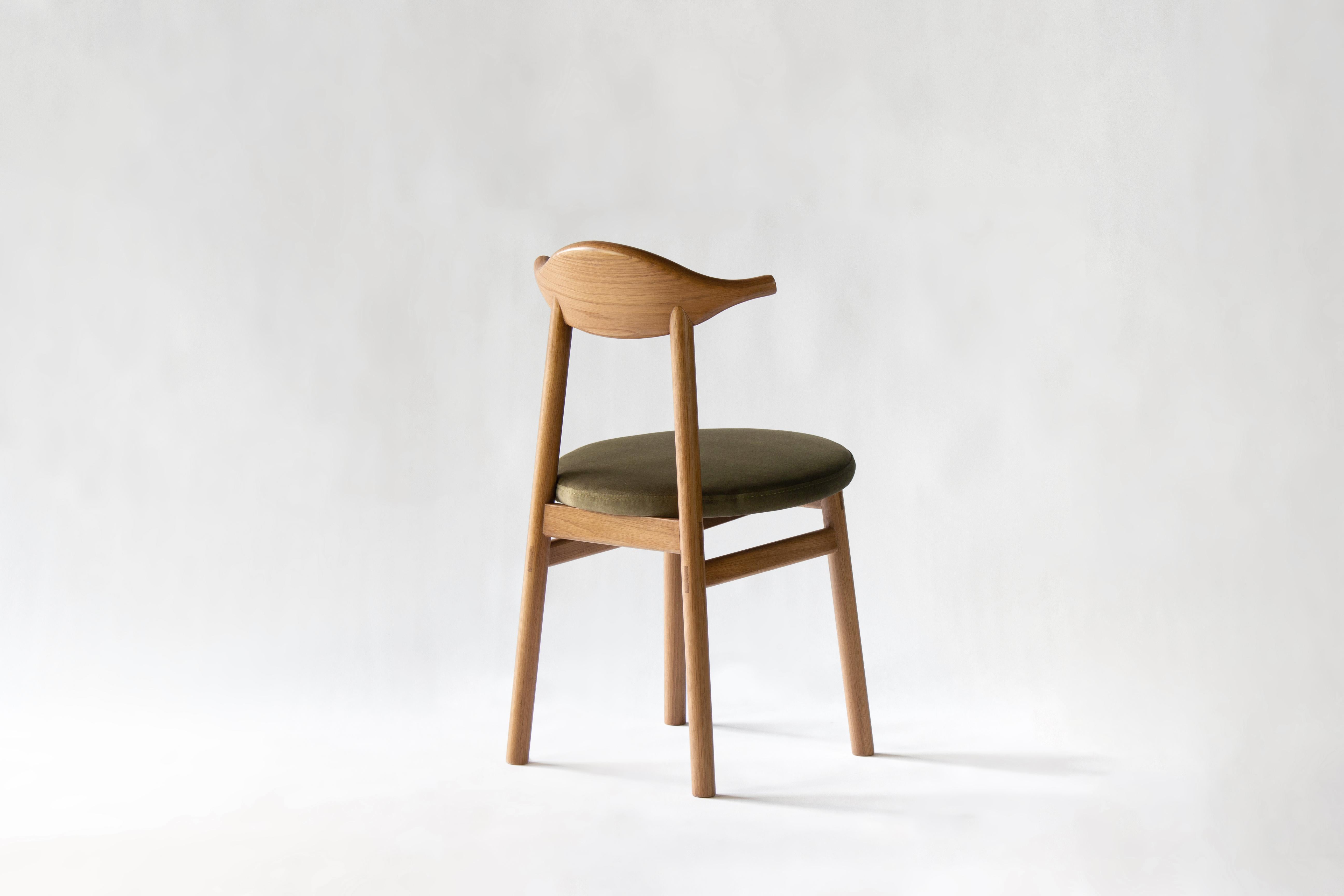 The Ember Chair is a versatile seat made using traditional joinery techniques. The wide, curved backrest is cut from solid white oak while the cushioned seat is encased in velvety, durable fabric meant for daily use. Also available with an all-wood