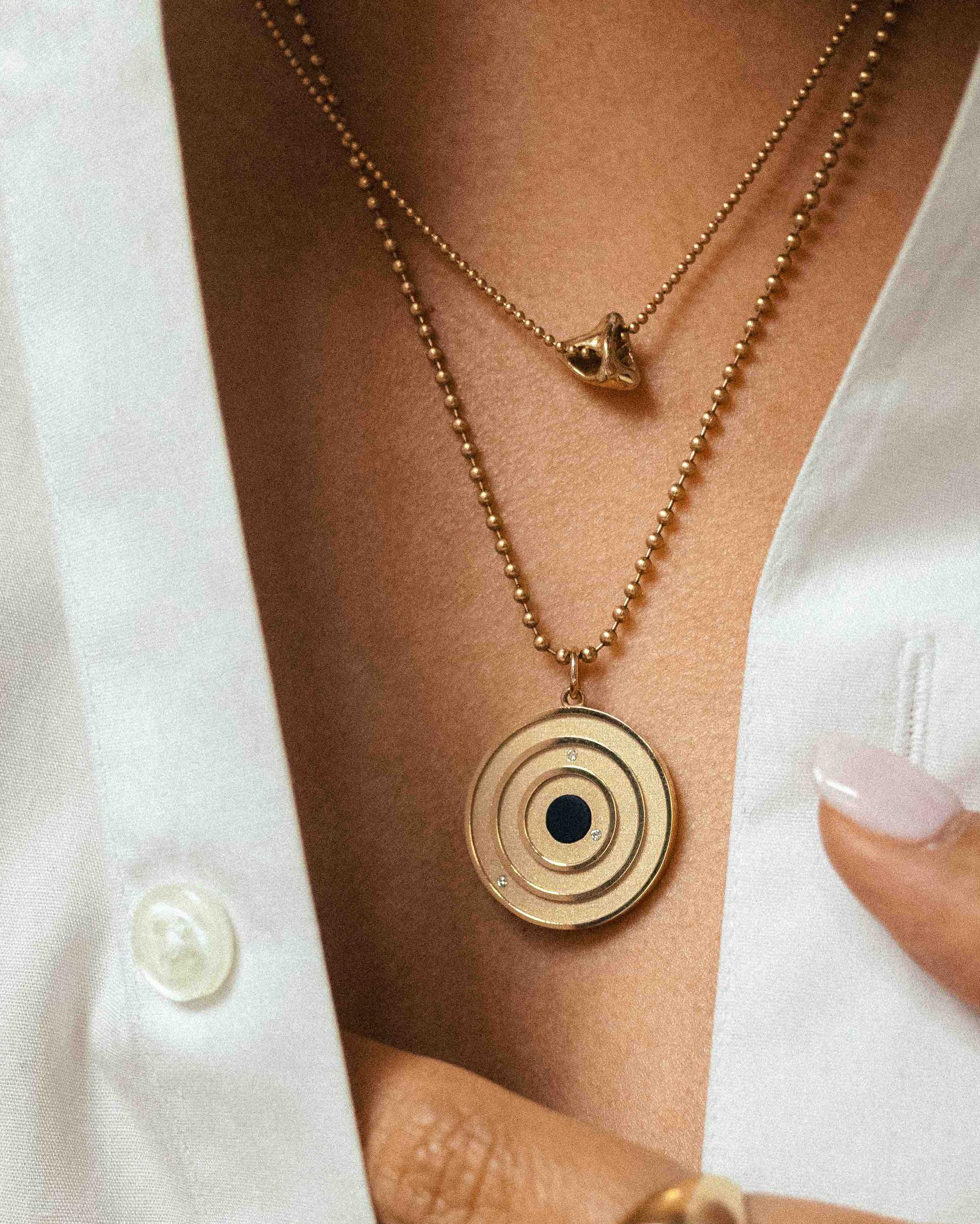 The Cosmos Pendant– designed and handmade by EMBLM Fine Jewelry

This circular pendant is cast in solid gold, with a sandblast finish beneath the concentric circle design. The external elements of the pendant are then high polished, creating a