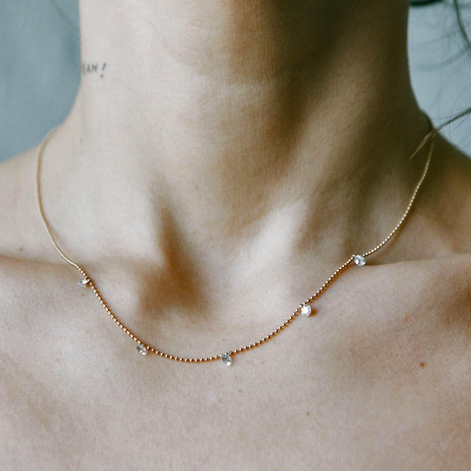 The Floating Diamond Necklace – designed and handmade by EMBLM Fine Jewelry

Like moonlight reflecting off of waves, the five white brilliant cut diamonds appear to float along the gold ball chain, a reminder to move with the tides of life.
