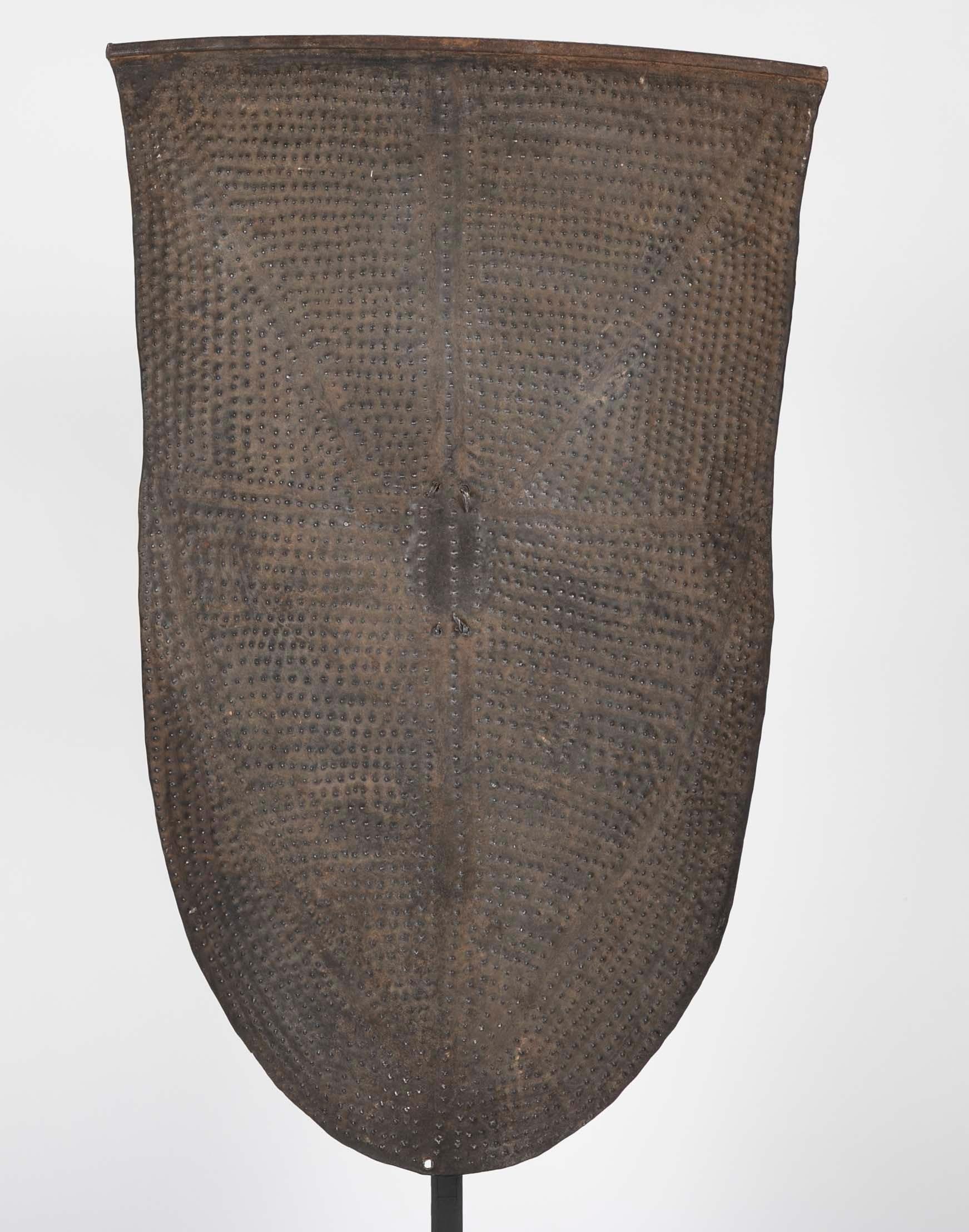 A rare repuse shield with natural fiber wraped handle from the Kirdi tribe Cameroon. Now on a patinated Bronze Stand. 

For a similar example please see- Benitez-Johannot, Purissima and Jean Paul Barbier, Shields: Africa, Southeast Asia and