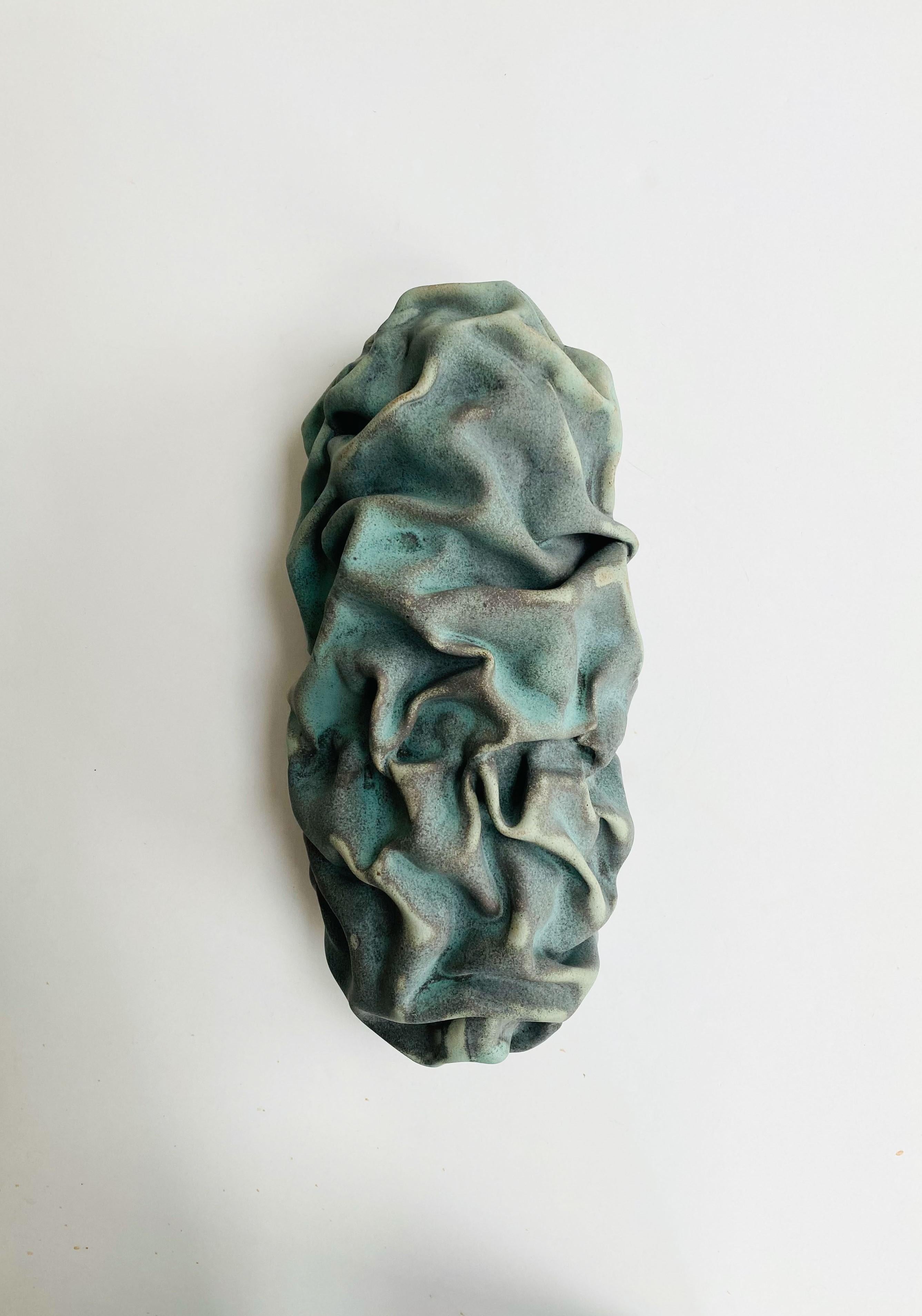 Emboss wall sculpture III by Sophie Rogers.
Dimensions: D 9 x W 15 x H 31 cm.
Materials: Ceramic, glaze.
Other glaze colors available.

Wall sculpture with undulating shape like a draped piece of cloth. Changes expression depending on the light