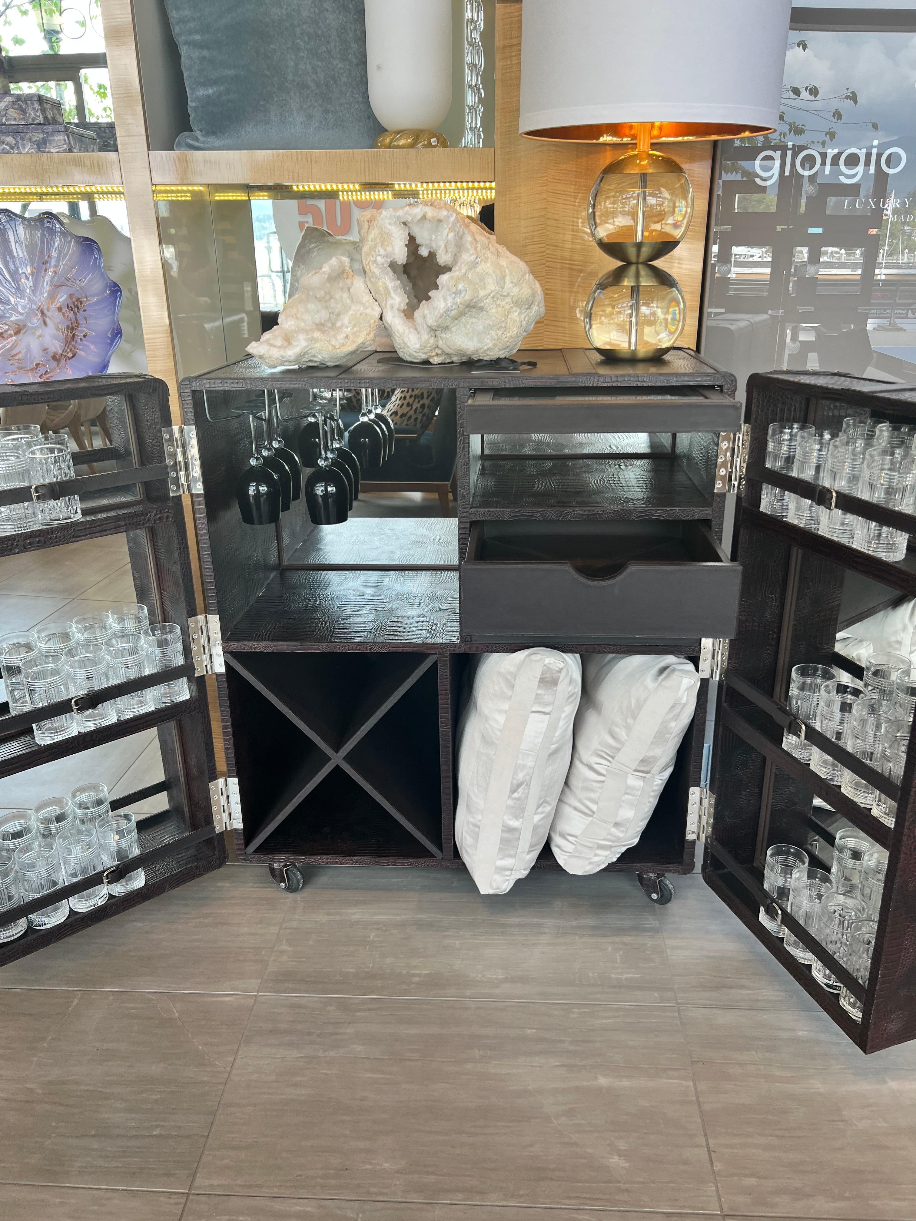 Own this amazing chocolate brown croc embossed leather rolling dry bar cabinet.
Mirror backed with french doors for glass and bottle storage.
Pull out beveled glass serving shelf and padded leather drawers for storage.