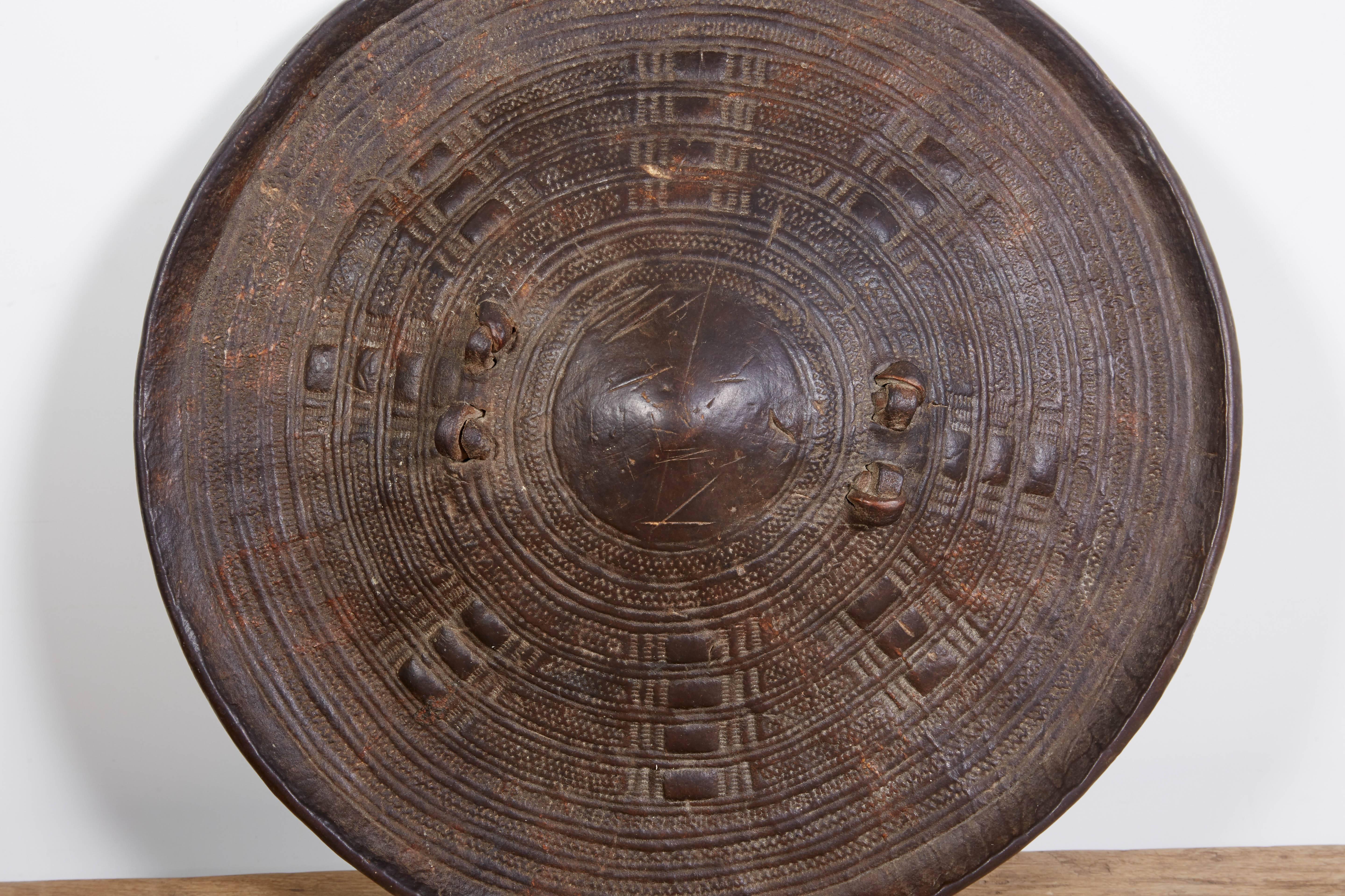 An intricately embossed hide shield from Somalia, circa 1960. 
This piece looks wonderful on a wall or shelf. Great conversation piece.
M215.