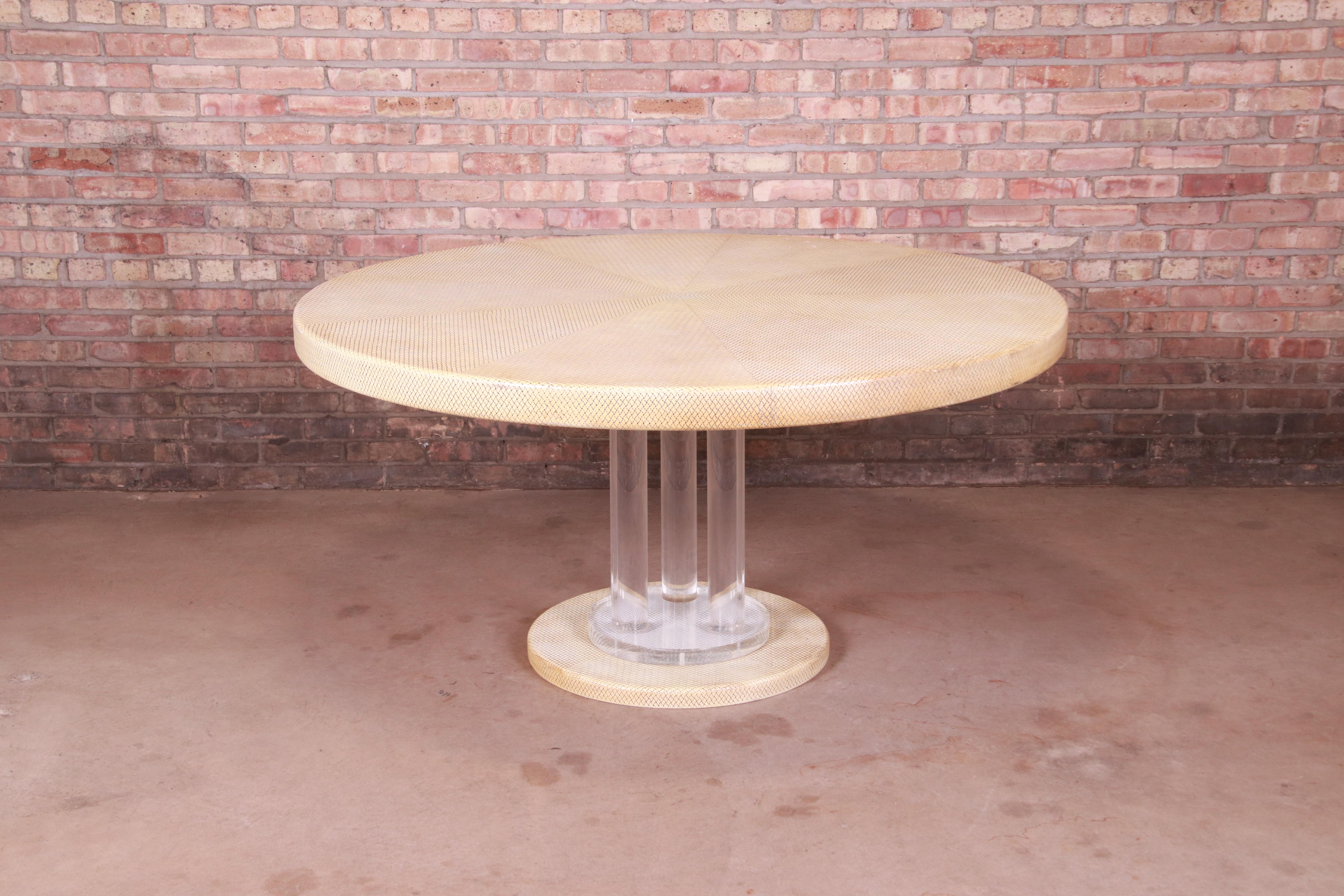 An exceptional Mid-Century Modern Hollywood Regency dining table or center table

In the manner of Karl Springer

USA, 1970s

Cream embossed leather top, with lucite pedestal base.

Measures: 60