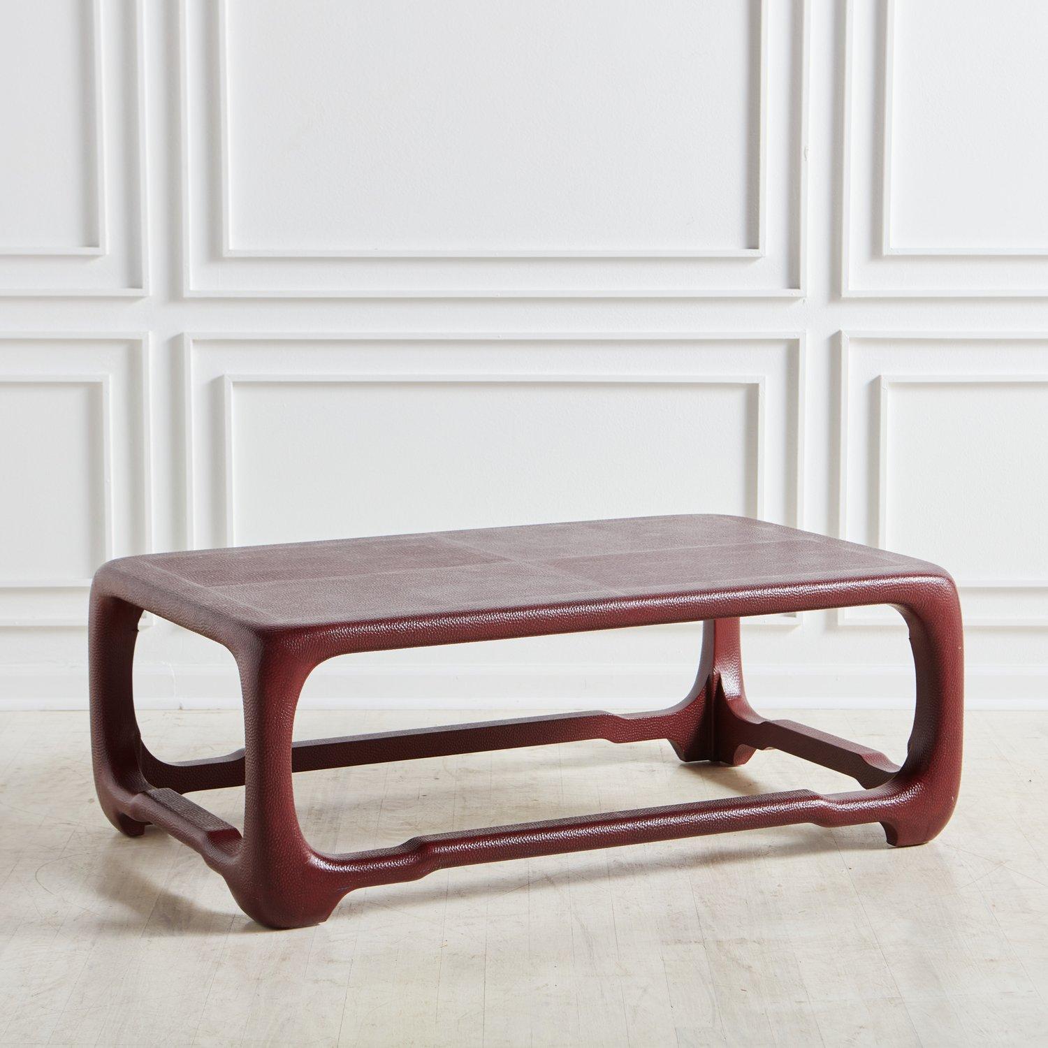 A rectangular embossed leather coffee table by Karl Springer. In a deep red with purple undertones, the embossed leather on this table features rich textural details. 

Karl Springer (1931-1991) was a prominent German-American designer known for