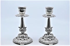 Embossed silver candlesticks with scrolls, florals and circular bases