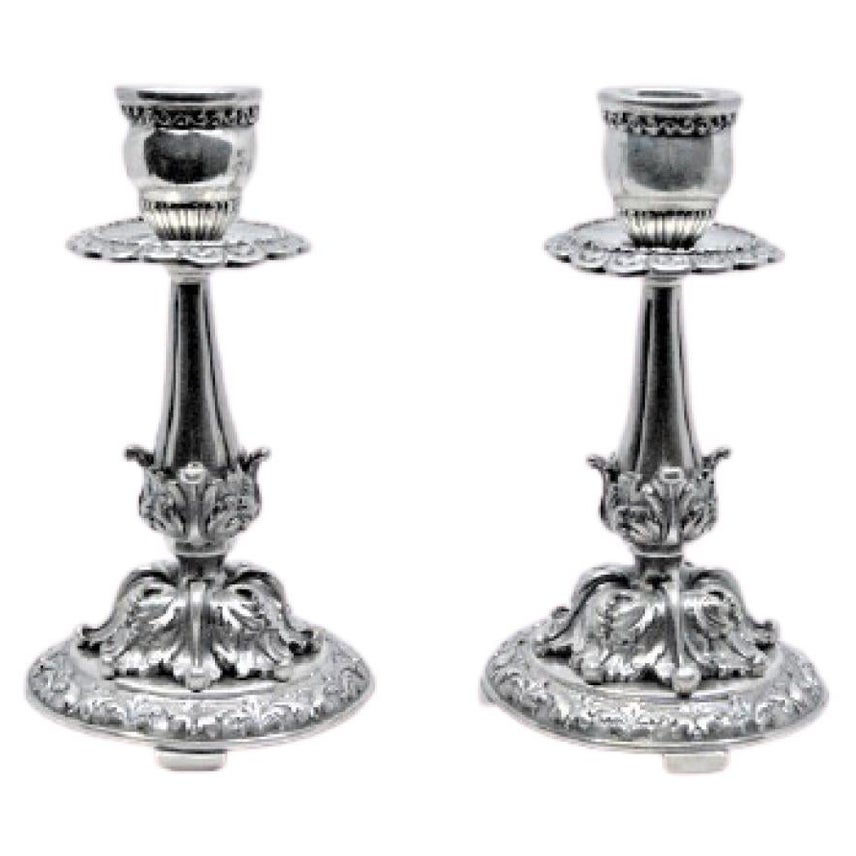 Embossed silver candlesticks with scrolls, florals and circular bases