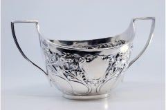 Embossed silver candy box with floral motifs, scrolls surrounding monogram cards