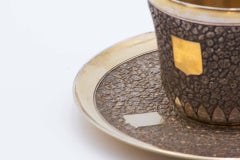Embossed silver cup and saucer with monogram and gold interior