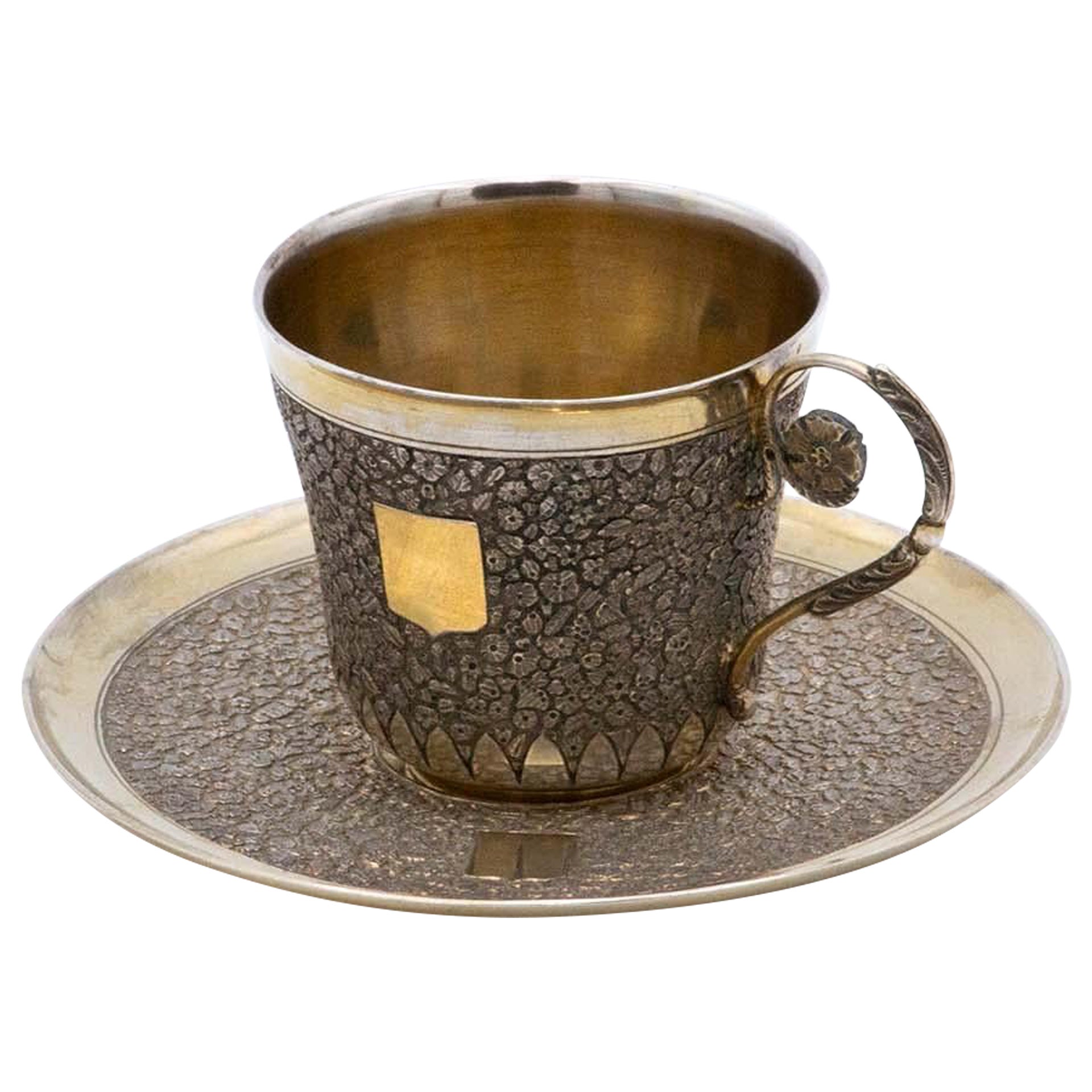 Embossed silver cup and saucer with monogram and gold interior