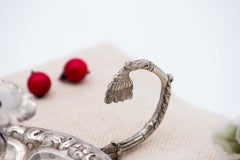 Embossed silver paddle with circular base and open handle