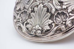 Embossed silver scullery with circular shells, lid knob and three cut-out feet