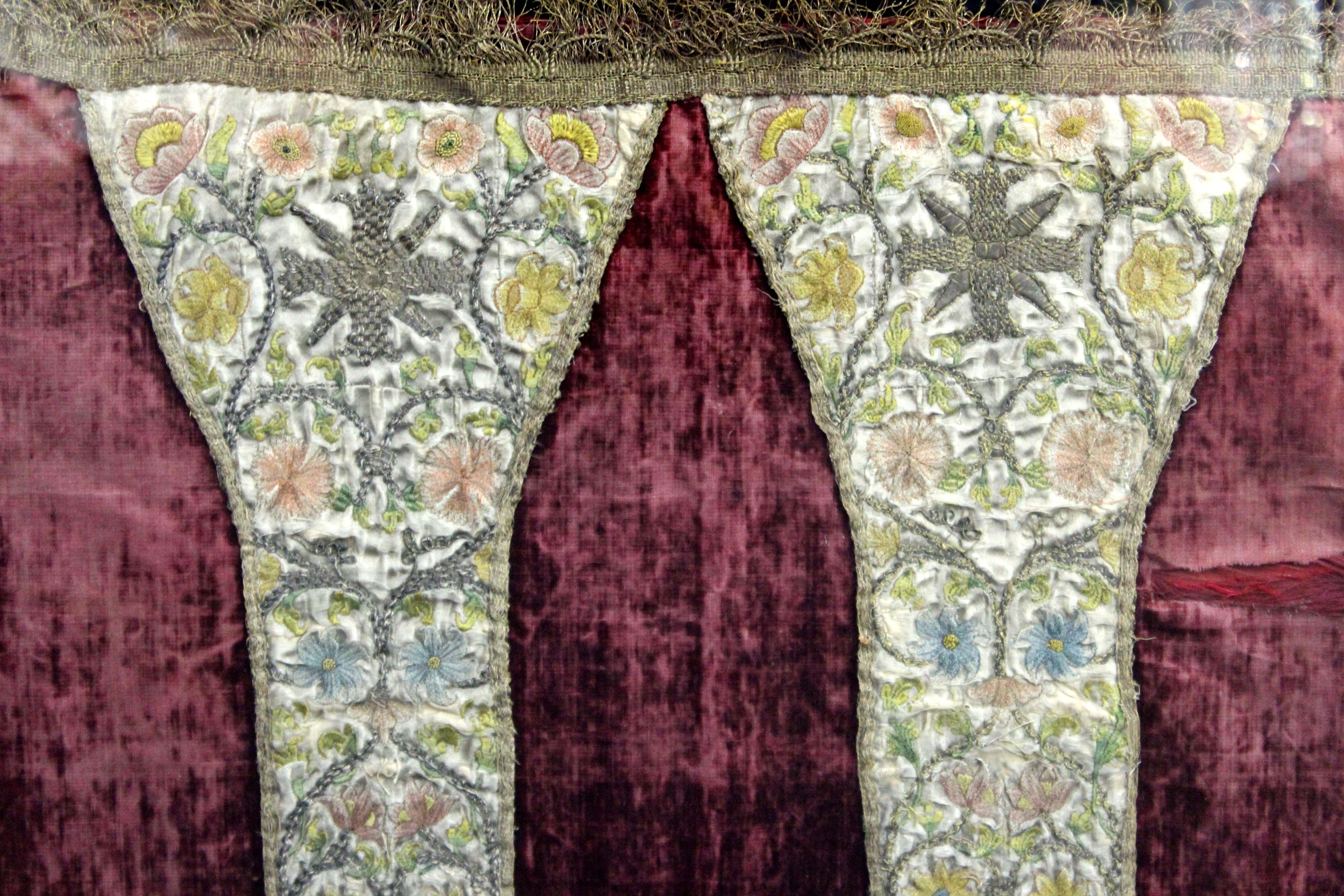 Antike bestickte Textilkasel mit floralen Ziermustern in Blau, Gelb und Rosa, wahrscheinlich im 17. bis 18. Jahrhundert in Europa hergestellt. Das Stück ist gerahmt und trägt auf der Rückseite eine Markierung, die darauf hinweist, dass es sich um