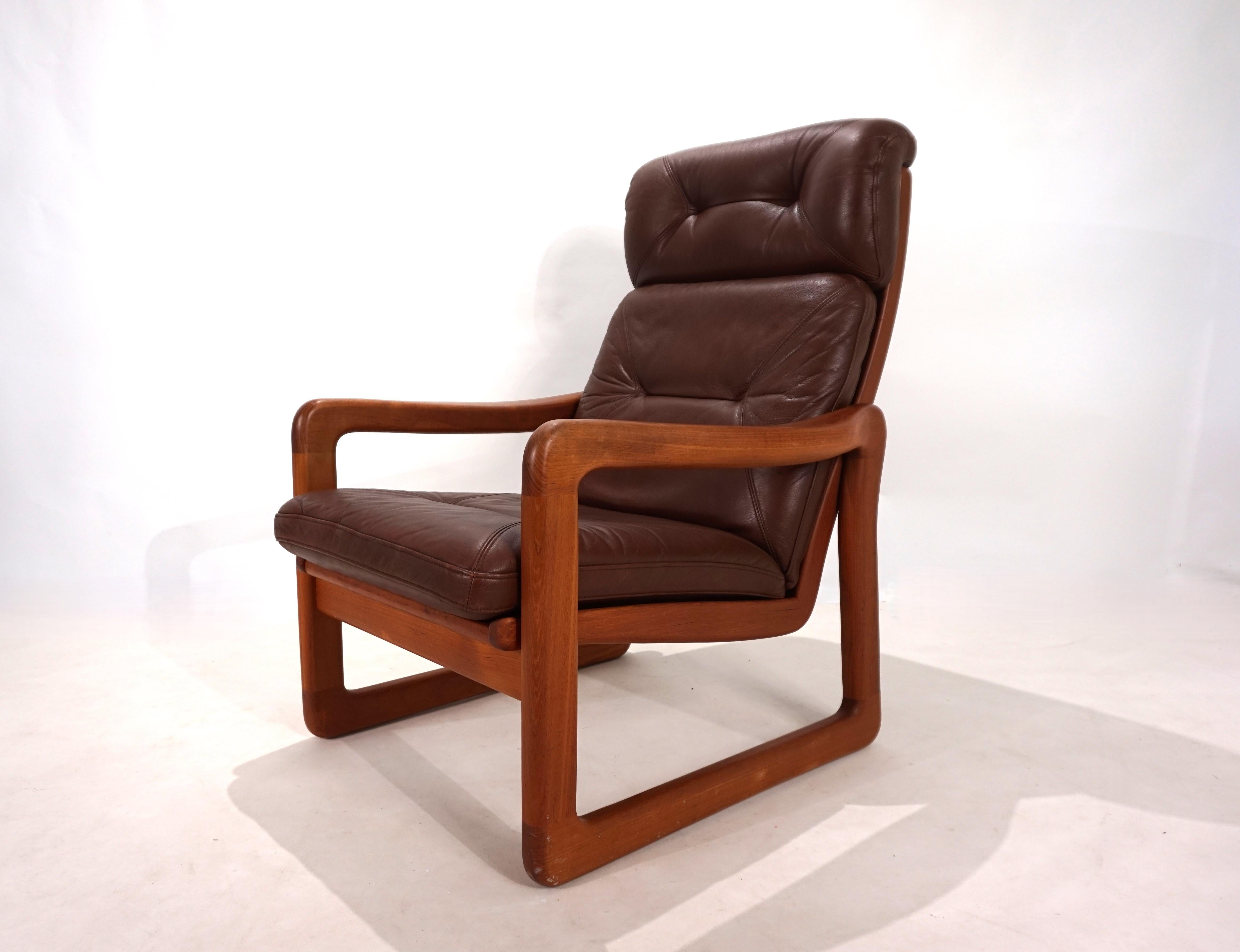 This teak armchair from EMC Mobler is in very good condition. The soft, chocolate-brown leather shows minimal signs of wear, and the cushions offer excellent seating comfort. Minimal patina on the corners of the headboard. The color of the leather