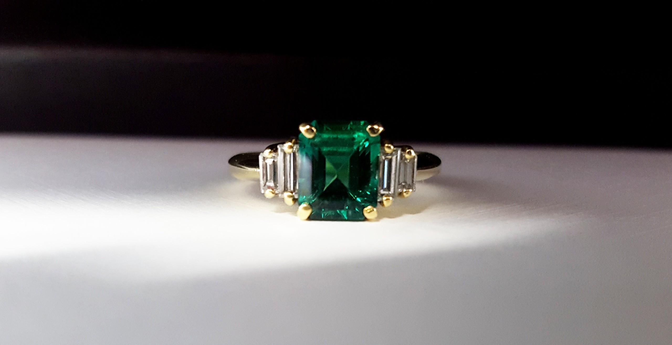 An 18 karat yellow gold ring set with 1 Emerald Cut Emerald and 4 Baguette Cut Diamonds. The Emerald measures 7.73 x 6.05 x 4.48mm and has an estimated weight of 1.60ct. The color is a fine medium green and the diamonds are H color VS2 clarity. All