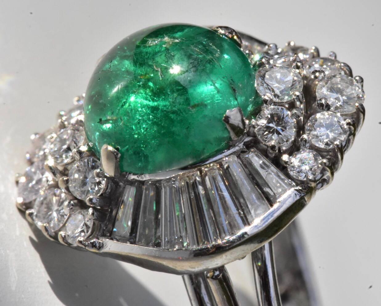 A fine Emerald and diamond ring set in 14k white gold. The ring features a cabochon emerald of approx 2.50 carat with trapeze and round brilliant-cut diamonds of approx 1.35 carat set to a plain 14k white gold band. 
Hallmarks: 585
Size: UK L 1/2,