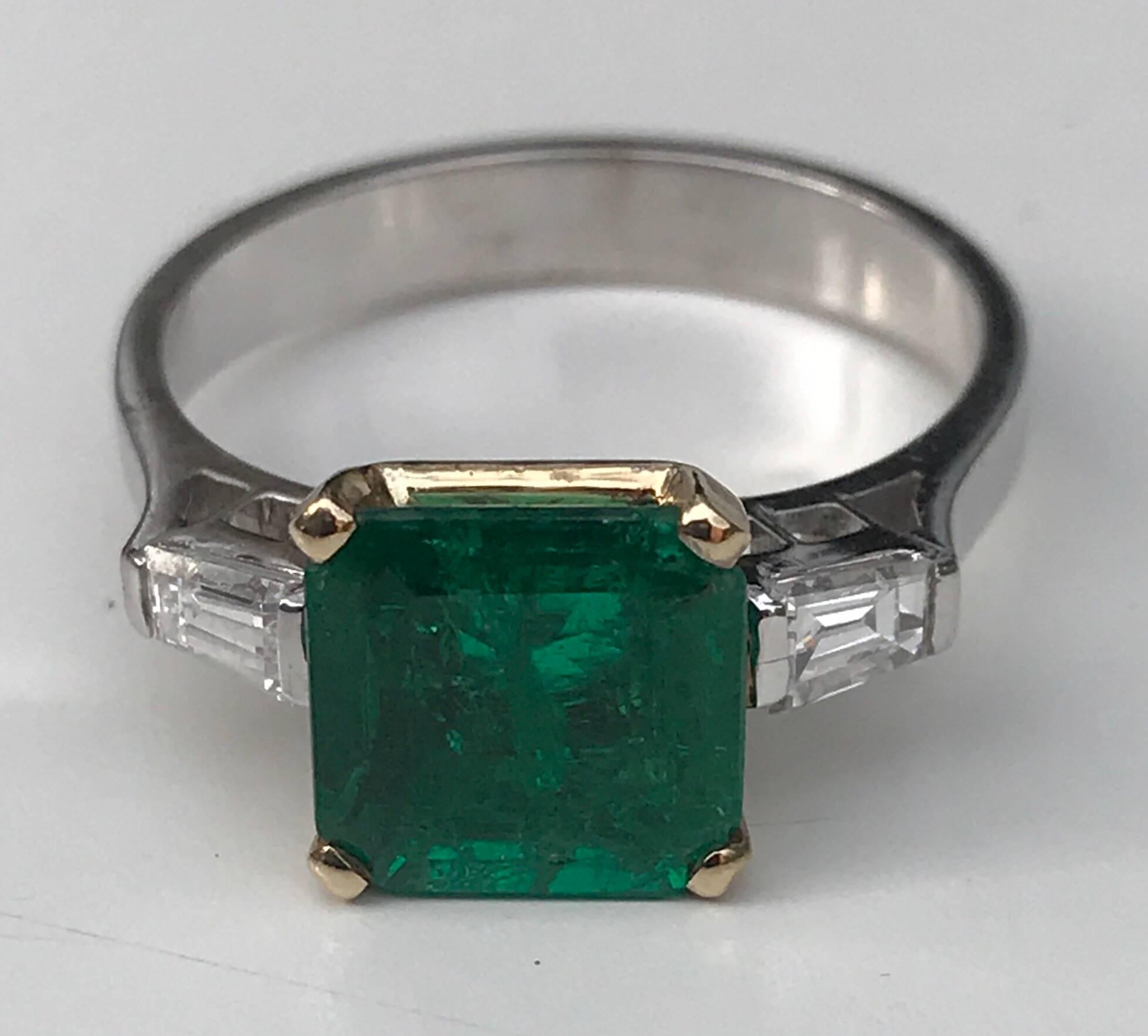 A fine Emerald and Diamond ring set in 18k white gold. The ring features an emerald-cut emerald of approx 1.76 carats with two radiant cut diamond side stones of approx .15 carats set to a plain white gold band
Hallmarks: unmarked
Weight: 4.5