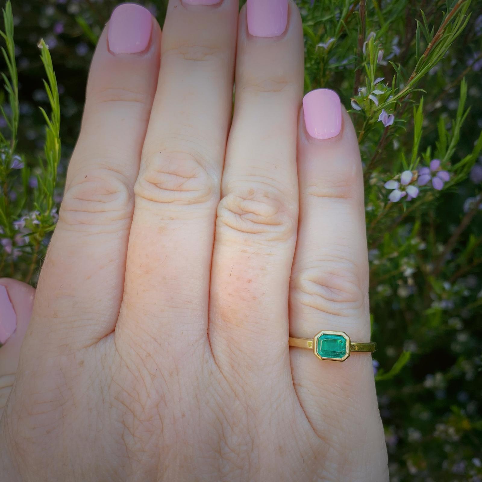 Dieser elegante und bezaubernde Ring aus 18 Karat Gelbgold zeigt einen leuchtend grünen Smaragd mit rechteckigem Schliff und einem Gewicht von 0,60 ct, der in einem modernen, maßgeschneiderten Design horizontal in die Lünette gefasst ist. Der Ring