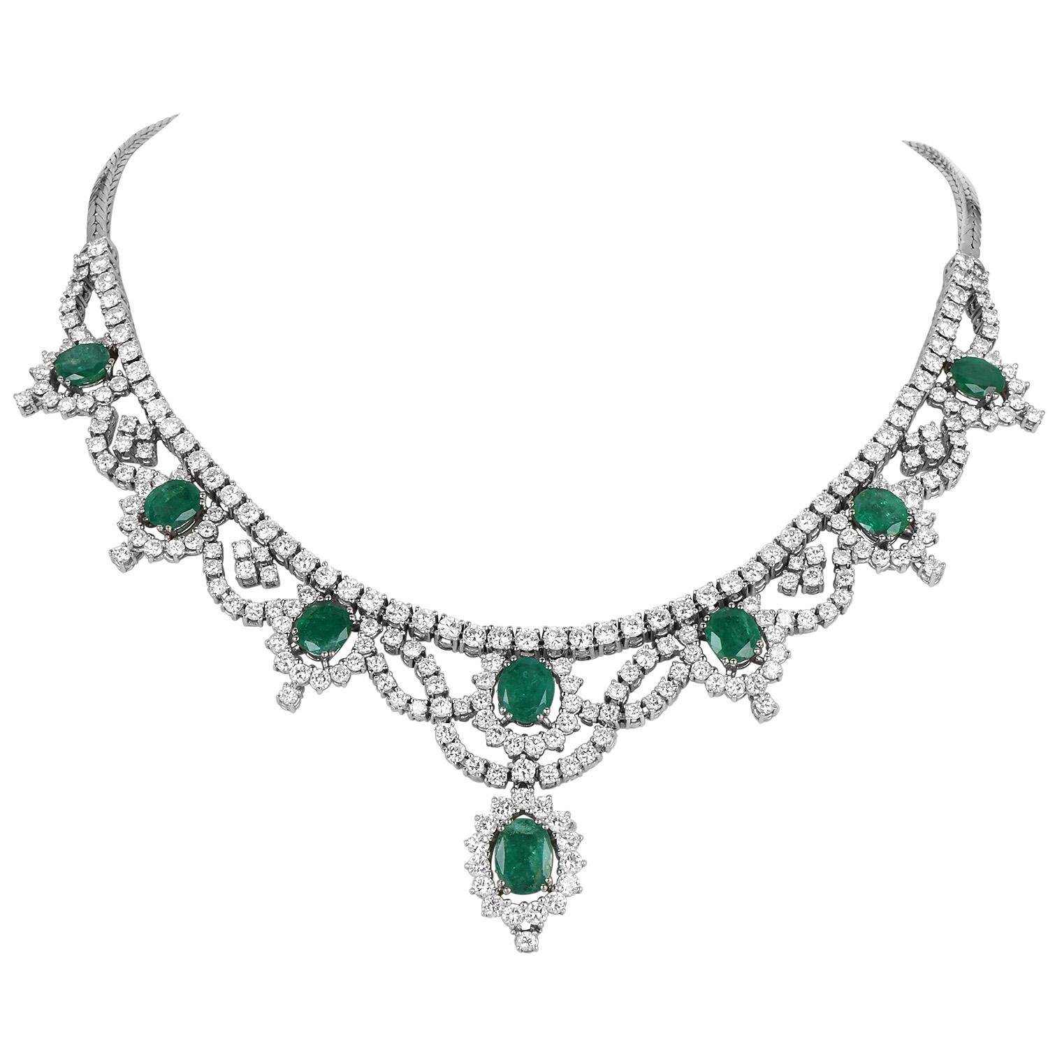 Collier draperie de grande classe en or blanc 18 carats, exquisément travaillé avec une cascade d'émeraudes naturelles et de diamants taillés en brillant. Ce collier présente huit émeraudes ovales, chacune entourée de diamants naturels dans une
