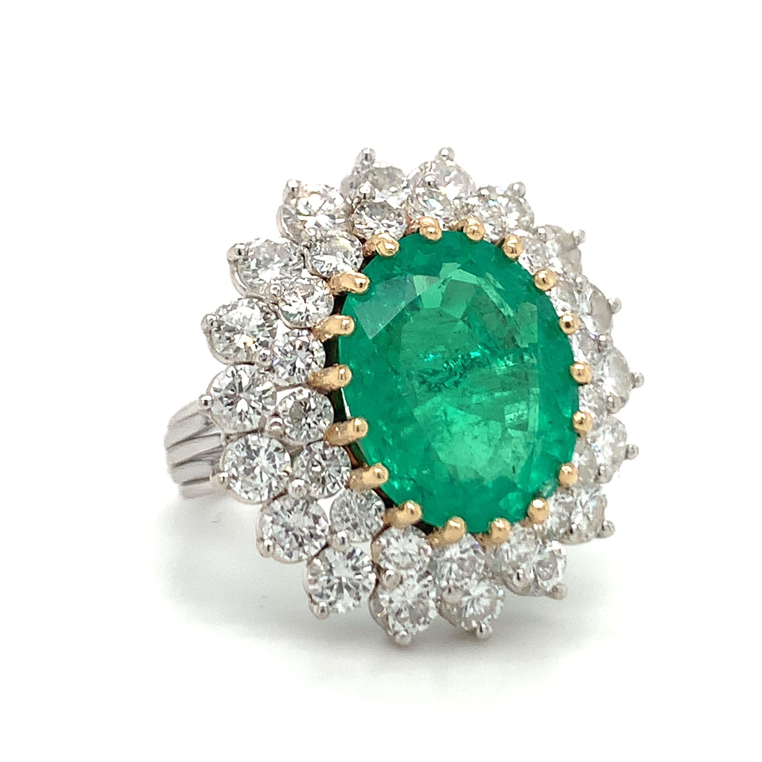 Emerald and diamond ring designed in 14K white gold featuring one yellow gold prong set, oval brilliant cut emerald weighing 6 ct. The emerald is surrounded by 36 round brilliant cut diamonds weighing 3 ct. with a G-H color and VS-2, SI-1
