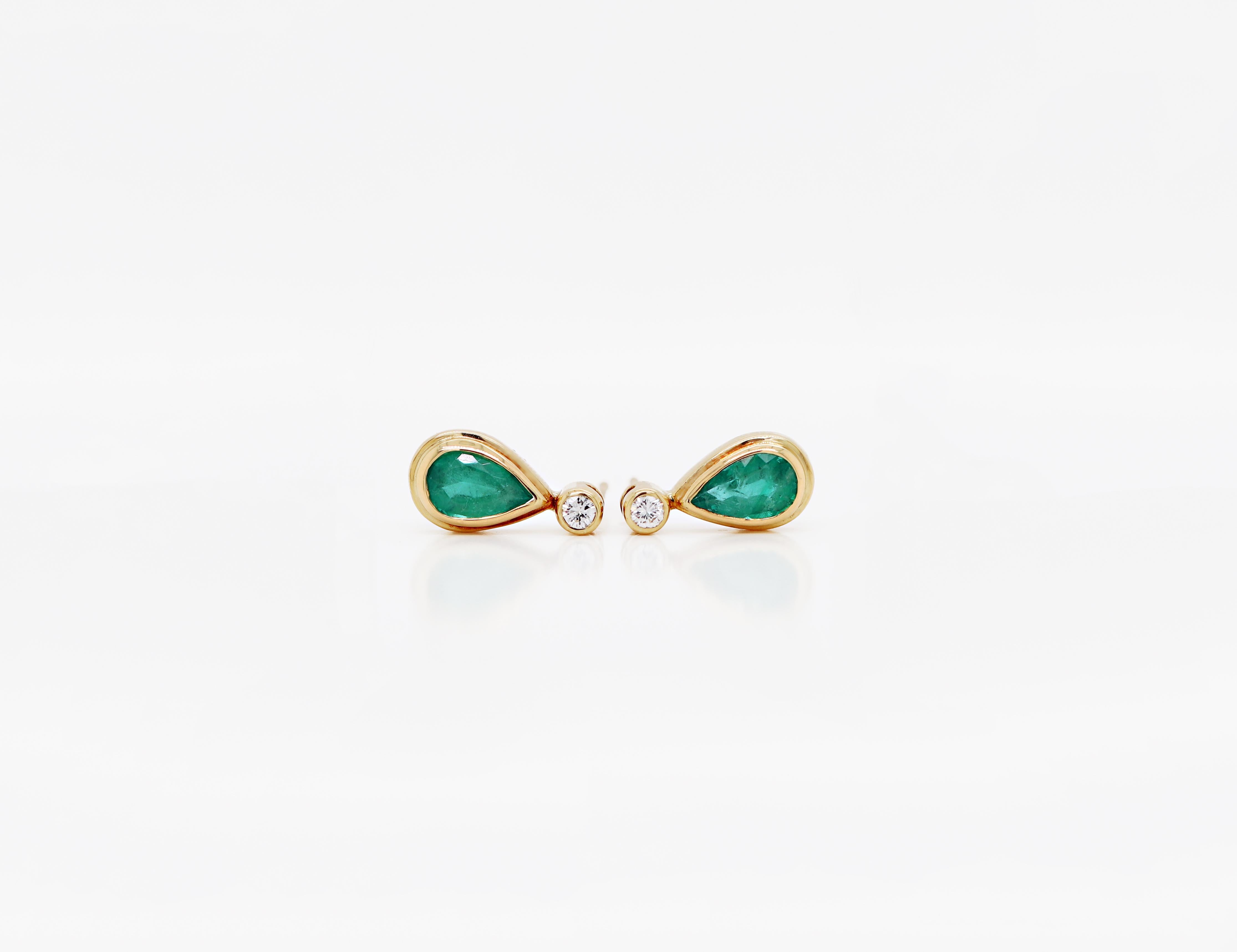 These beautiful earrings feature a vibrant pear shaped emerald weighing approximately 1.00ct each, mounted in a rub over, open back setting. The emerald is wonderfully accompanied by a fine quality round brilliant cut diamond above it, weighing