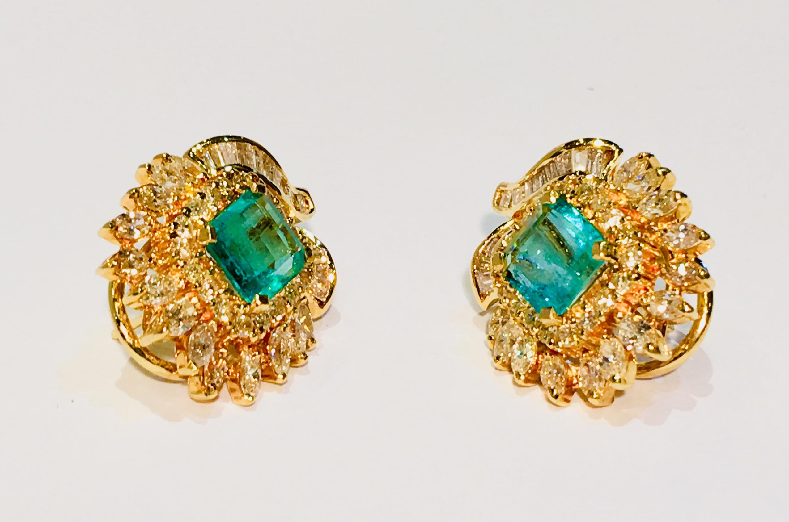 Beautiful pair of custom made estate floral motif earrings feature large, prong set, emerald cut emeralds surrounded by prong set, round brilliant and marquise cut diamonds, and channel set, baguette cut diamonds in 18 karat yellow gold with posts