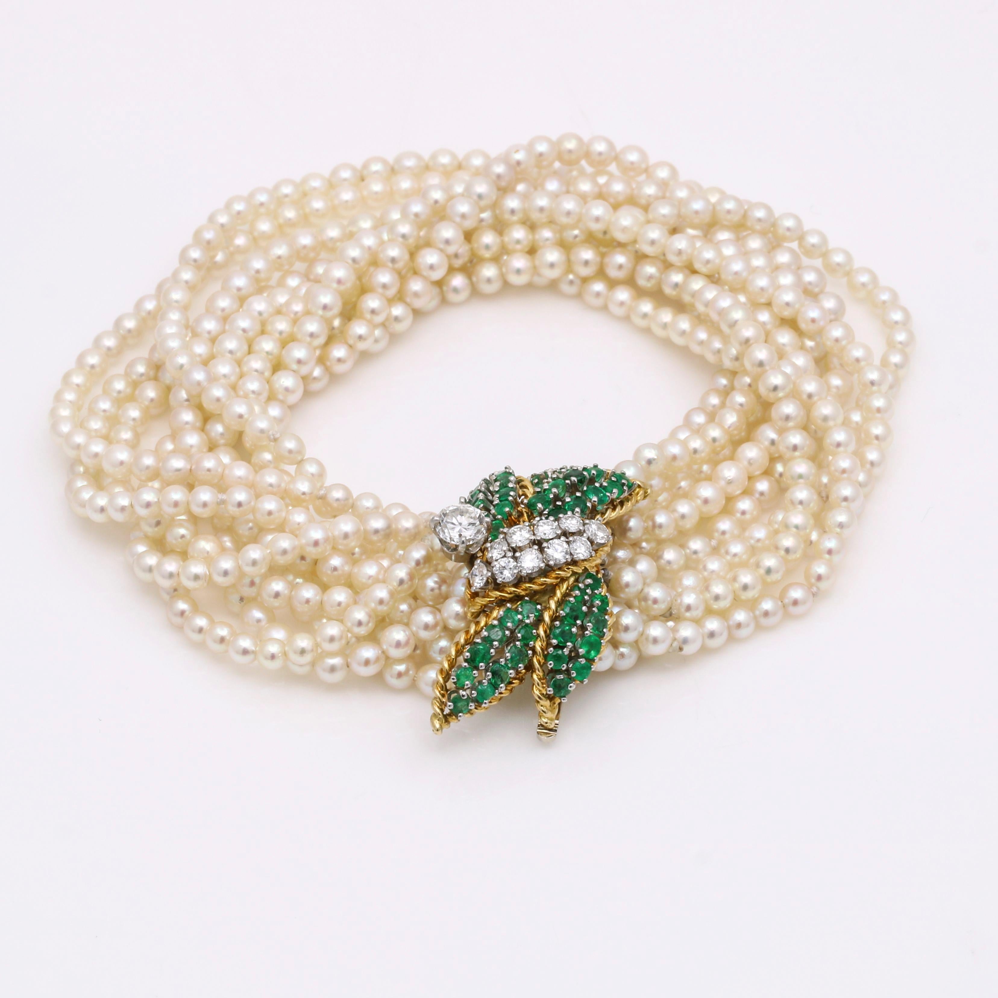 This beautiful diamond and emerald multi-strand pearl bracelet is a timeless piece of fine jewelry. The elegant leaves clasp crafted of 18k yellow gold and encrusted with emeralds and diamonds adds stunning detail to the overall design. The round