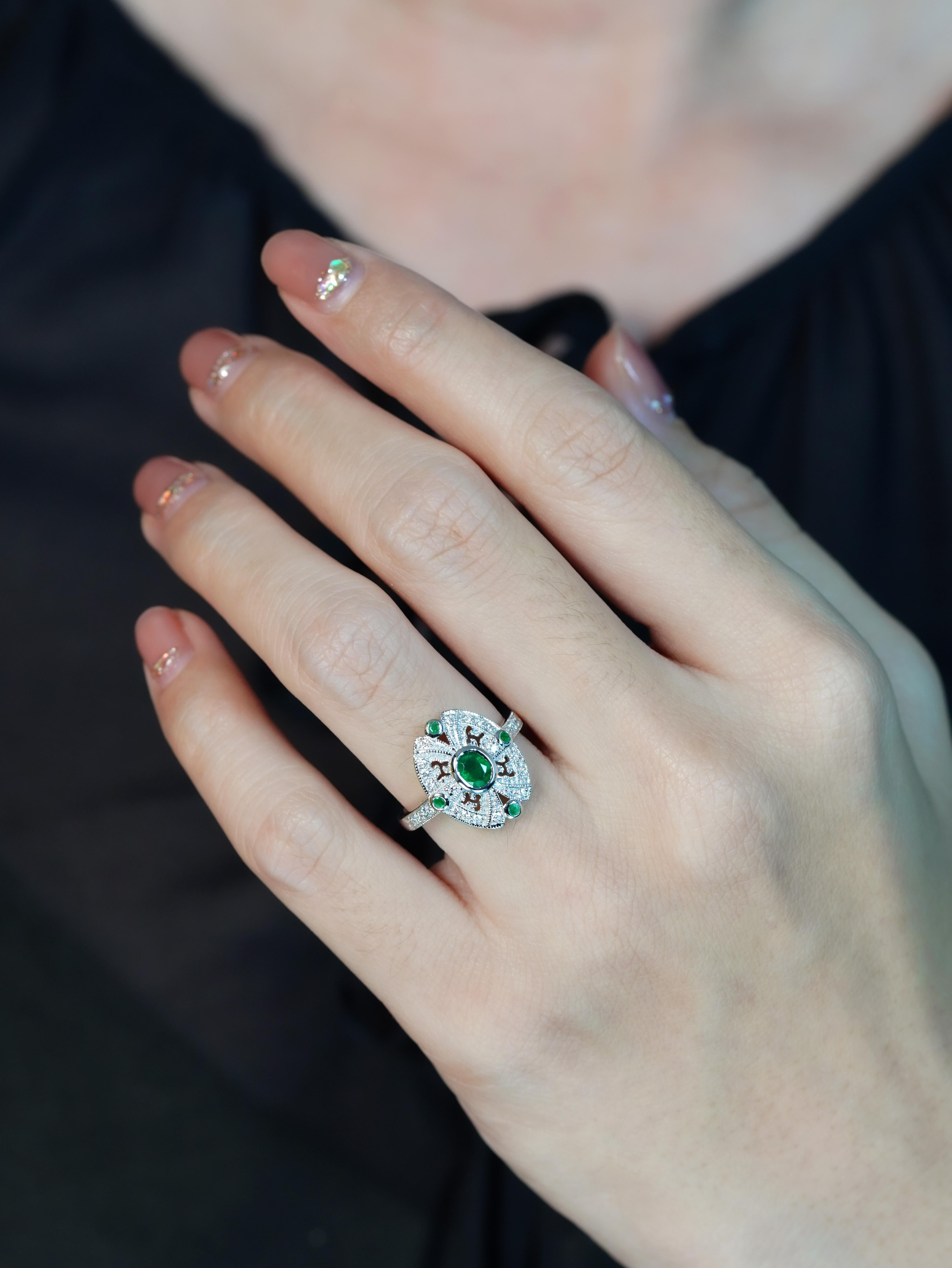 L'anello aureola con smeraldo e diamante in oro bianco di Elegiting incarna l'eleganza e le caratteristiche dei gioielli in stile Art Deco. Con uno smeraldo ovale incastonato al centro, l'anello è impreziosito da ventiquattro diamanti e altri