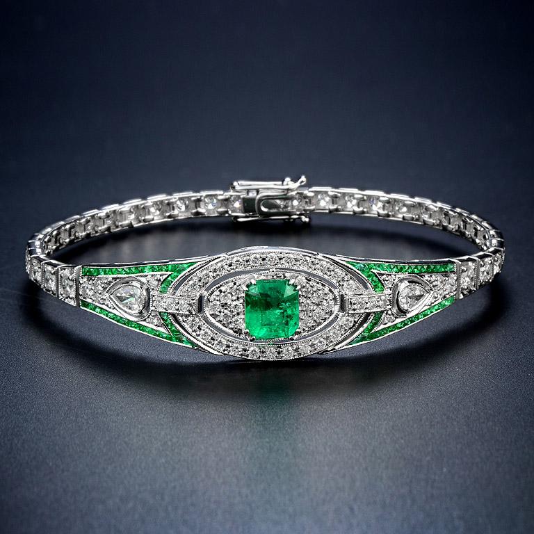 This luminous and luxurious Art Deco style jewel features a center approx. 2.16 carat emerald, framed by approx. 2.16 carat glittering round diamonds and vibrant green French cut emeralds. A slender, streamlined and simply stunning Art Deco design