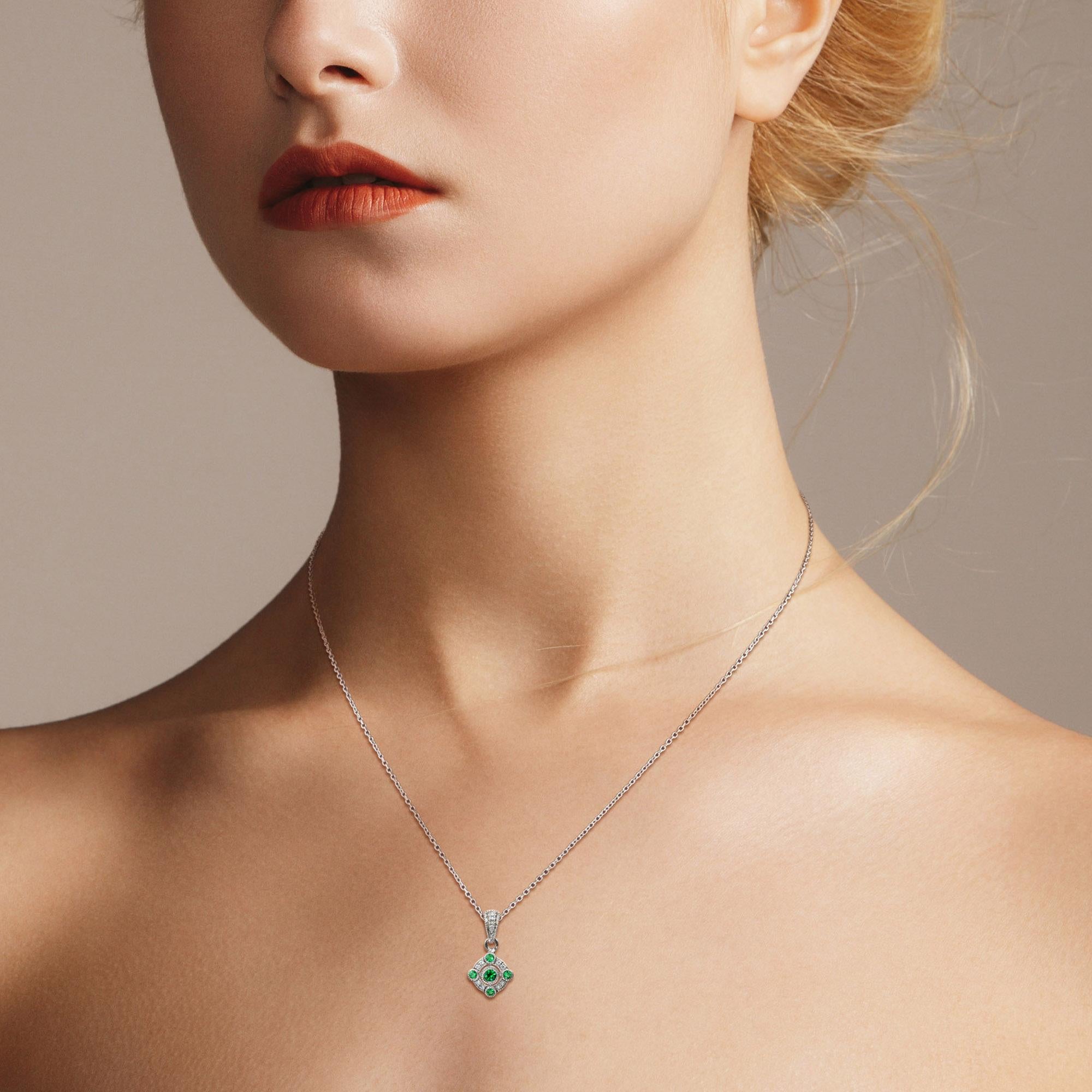 With pretty vintage styling, this pendant makes the perfect finishing touch to an outfit. Featuring five emeralds and ten round brilliant cut diamonds that give a subtle, glittering appearance. The edges of the design have millgrain detailing to