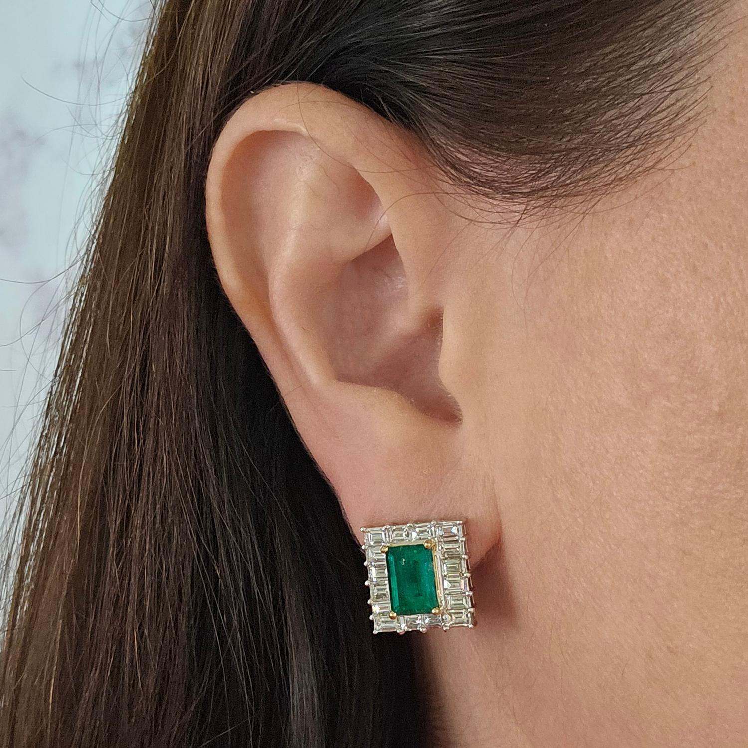 18 Karat White and Yellow Gold Earrings Featuring 2 Elongated Emeralds Totaling 3.30 Carats Surrounded by 32 Baguette Cut Diamonds of SI Clarity and H Color Totaling Approximately 3.00 Carats. Pierced Post with Omega Clip Back. Post Removed Upon