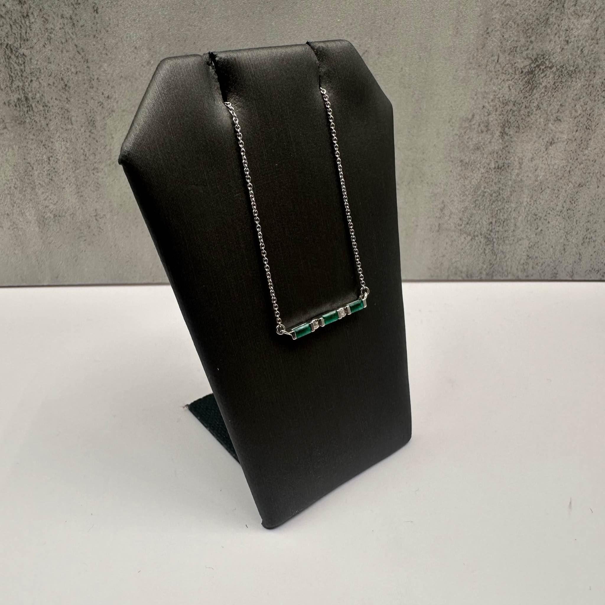 Este elegante Collar con Barra de Esmeraldas y Diamantes de plata de ley presenta tres esmeraldas talla baguette de 4x2 mm, acentuadas por 0,01 ctw de diamantes redondos talla única de calidad I, I naturales engastados en un engaste milagroso de