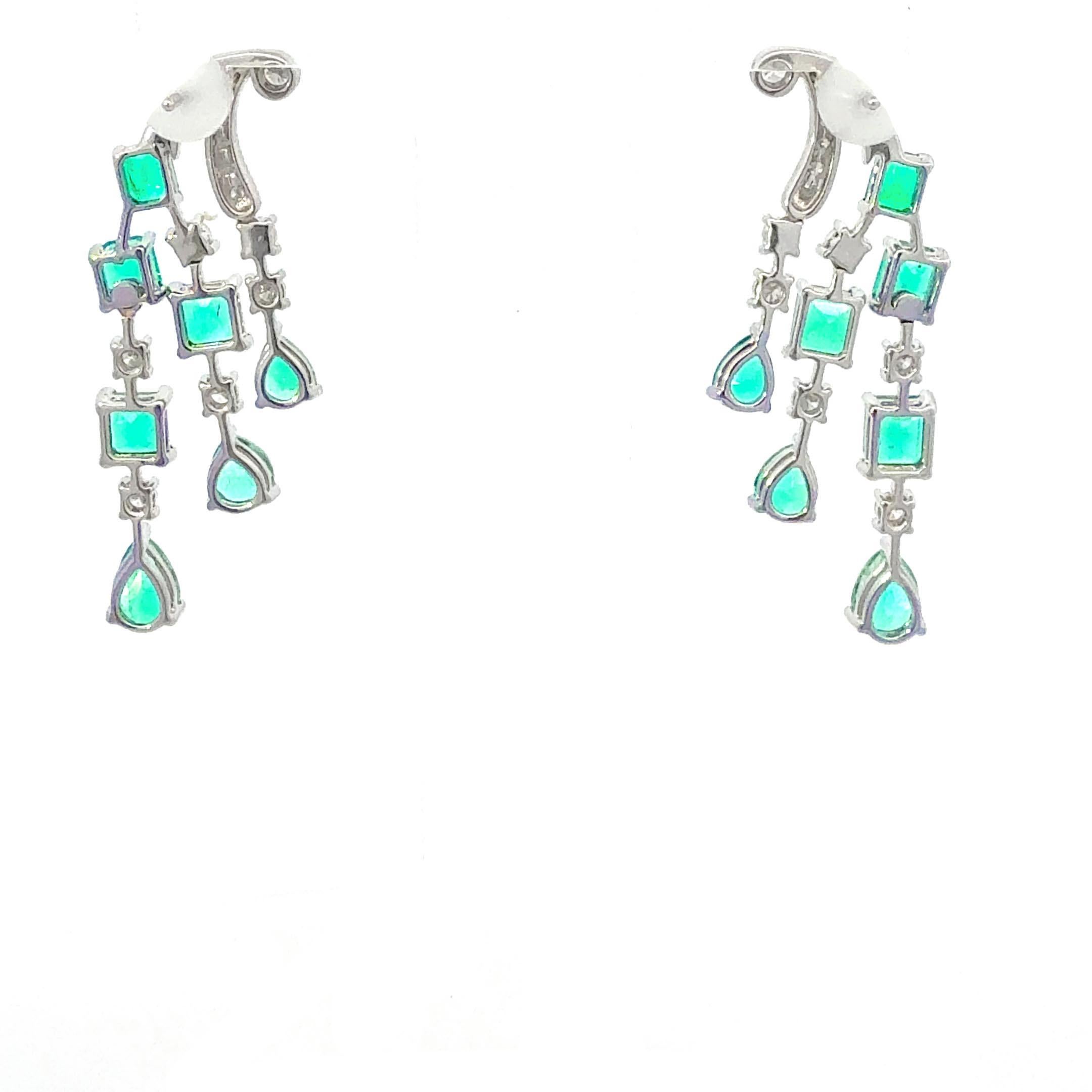 Cascading emerald and diamond chandelier drop earrings crafted in luminous 18 karat white gold, showcasing 5.74 carats of vivid green emeralds and 0.86 carats of brilliant white diamonds. These elegant dangle earrings feature a harmonious blend of