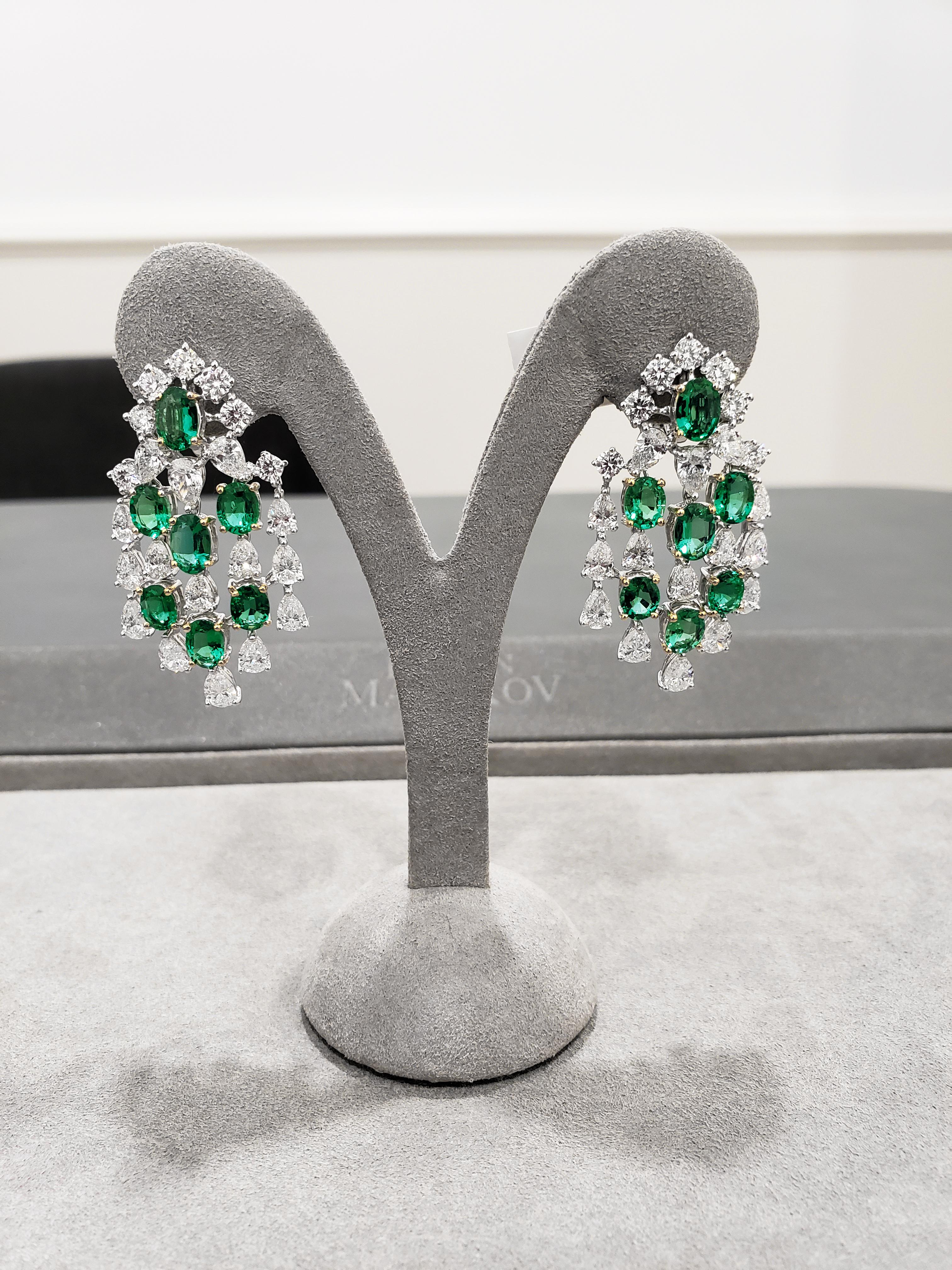 A stunning pair of earrings showcasing 14 vibrant oval cut green emeralds weighing 7.49 carats total; accented by 9.90 carats total of dazzling round and pear shaped diamonds. Intricately designed and expertly handcrafted to perfection. A truly