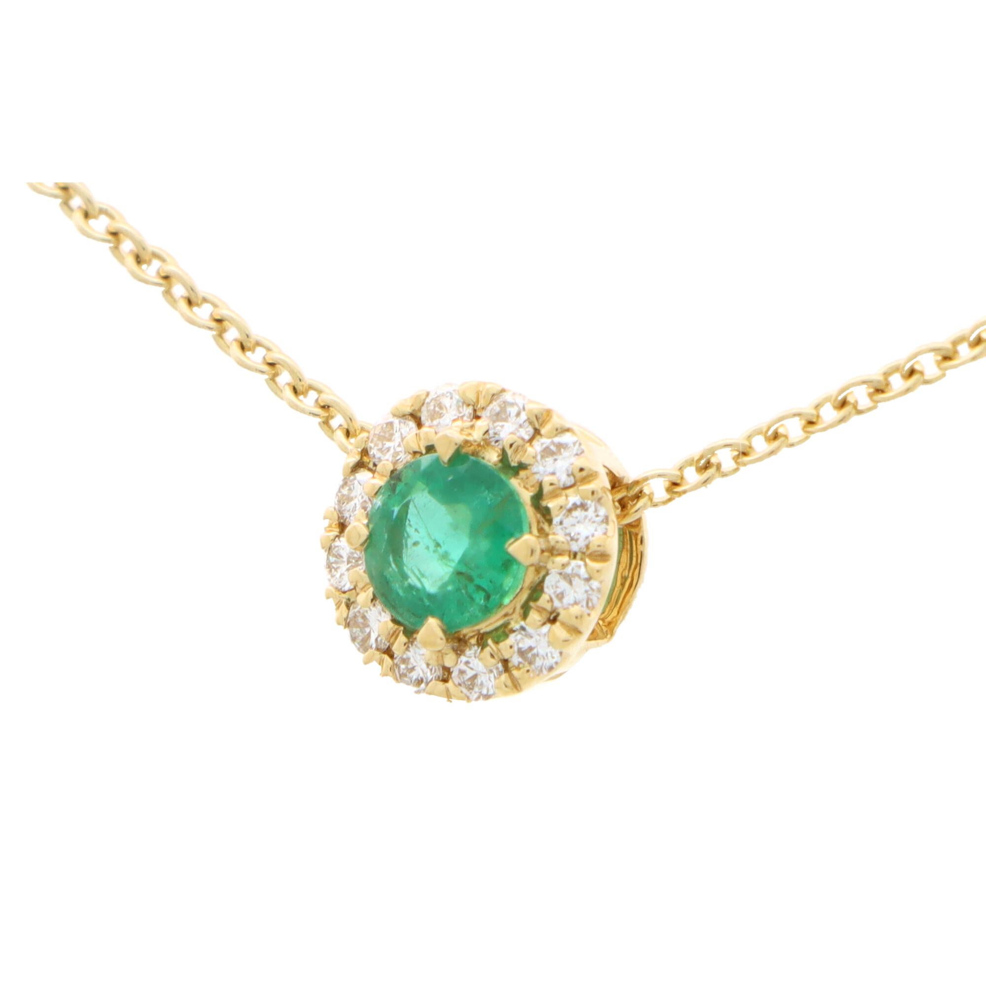 A beautiful emerald and diamond cluster pendant set in 18k yellow gold.

The pendant is centrally set with a vibrant green coloured round cut emerald which is surrounded by 12 sparkly round brilliant cut diamonds. The pendant hangs from a 9k yellow